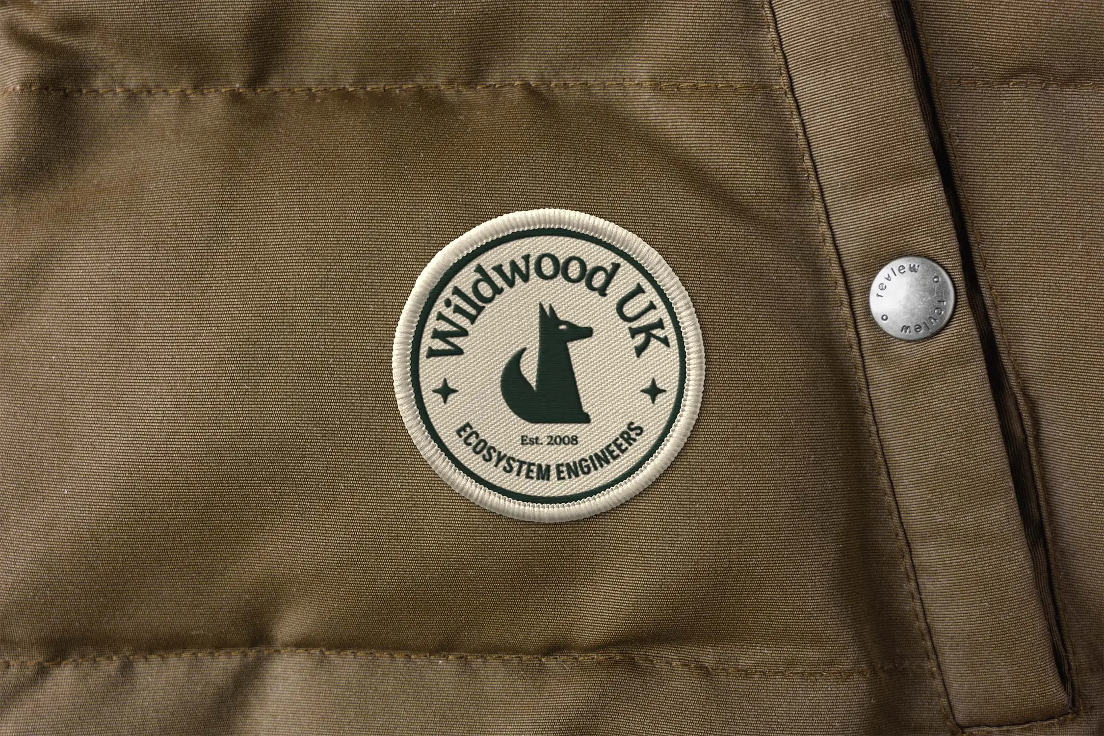 Close-up of a brown jacket with a circular logo featuring a stylized animal design and text.