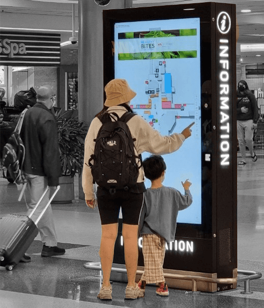 A photo of an adult and child using a map on an interactive kiosk