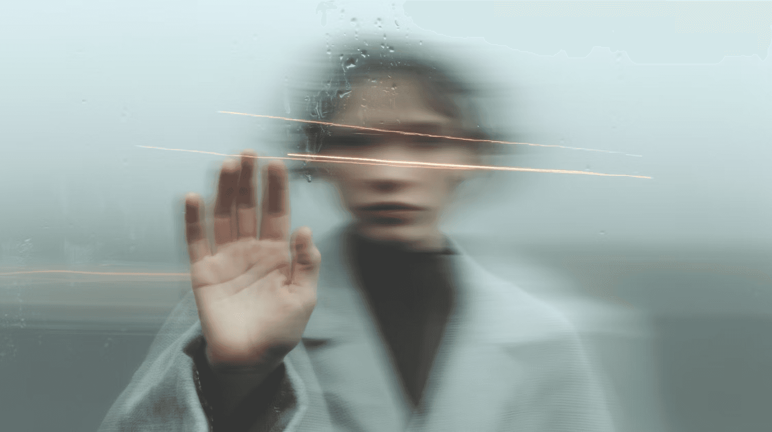 Blurred figure behind a foggy glass with water droplets, hand pressed against the surface, creating a mysterious and artistic vibe.