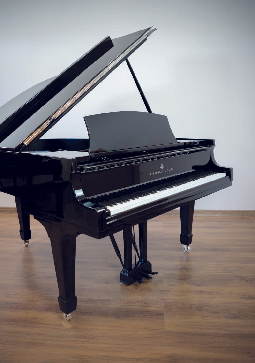 A fully restored black Steinway & Sons grand piano with a glossy polyester finish, reflecting elegance and precision.