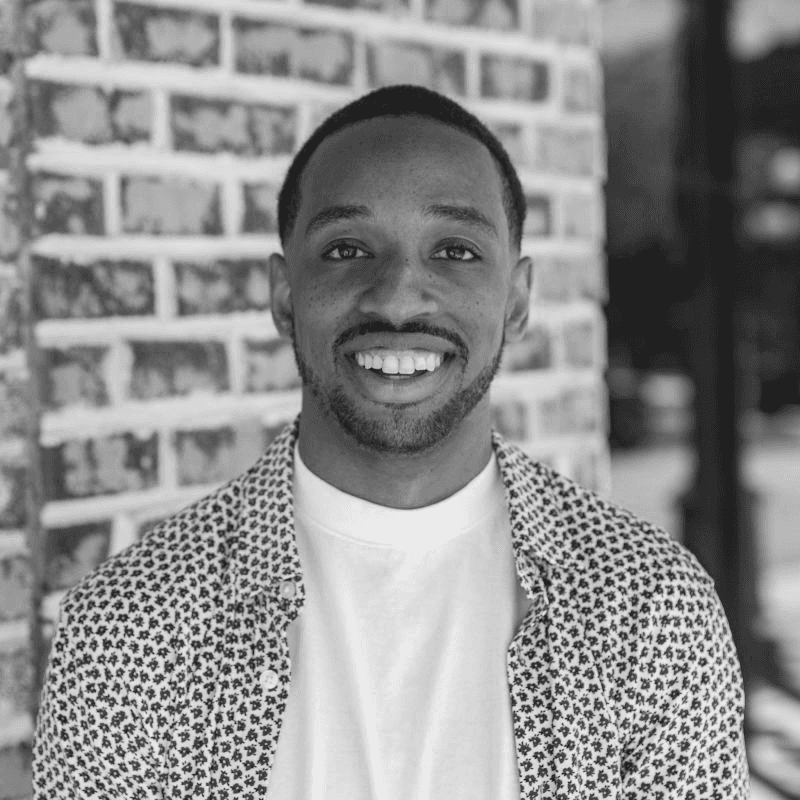 A thoughtful young person with dark hair gazes to the side, captured in soft black and white lighting.