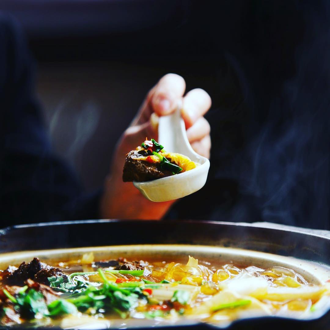 A steaming bowl of rich lamb soup, garnished with fresh herbs and featuring tender cuts of lamb in a savory broth, highlighting the flavors of northwest Chinese halal cuisine.