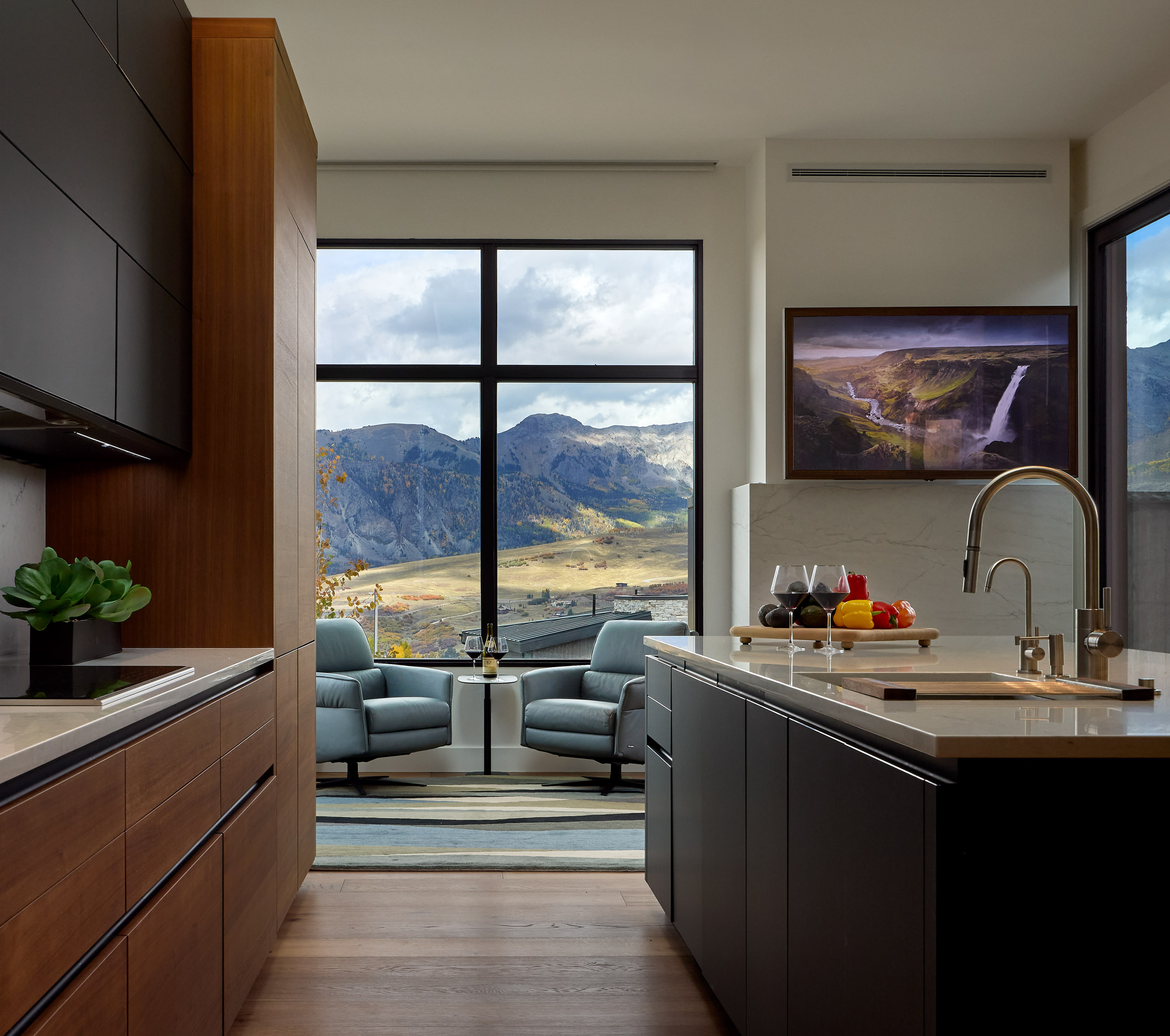 Modern kitchen with mountain view, 2 armchairs, and waterfall on TV