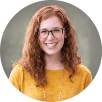 Headshot of Rachel Drumm, smiling with long curly red hair and glasses. She is the Director of Communications & Development.