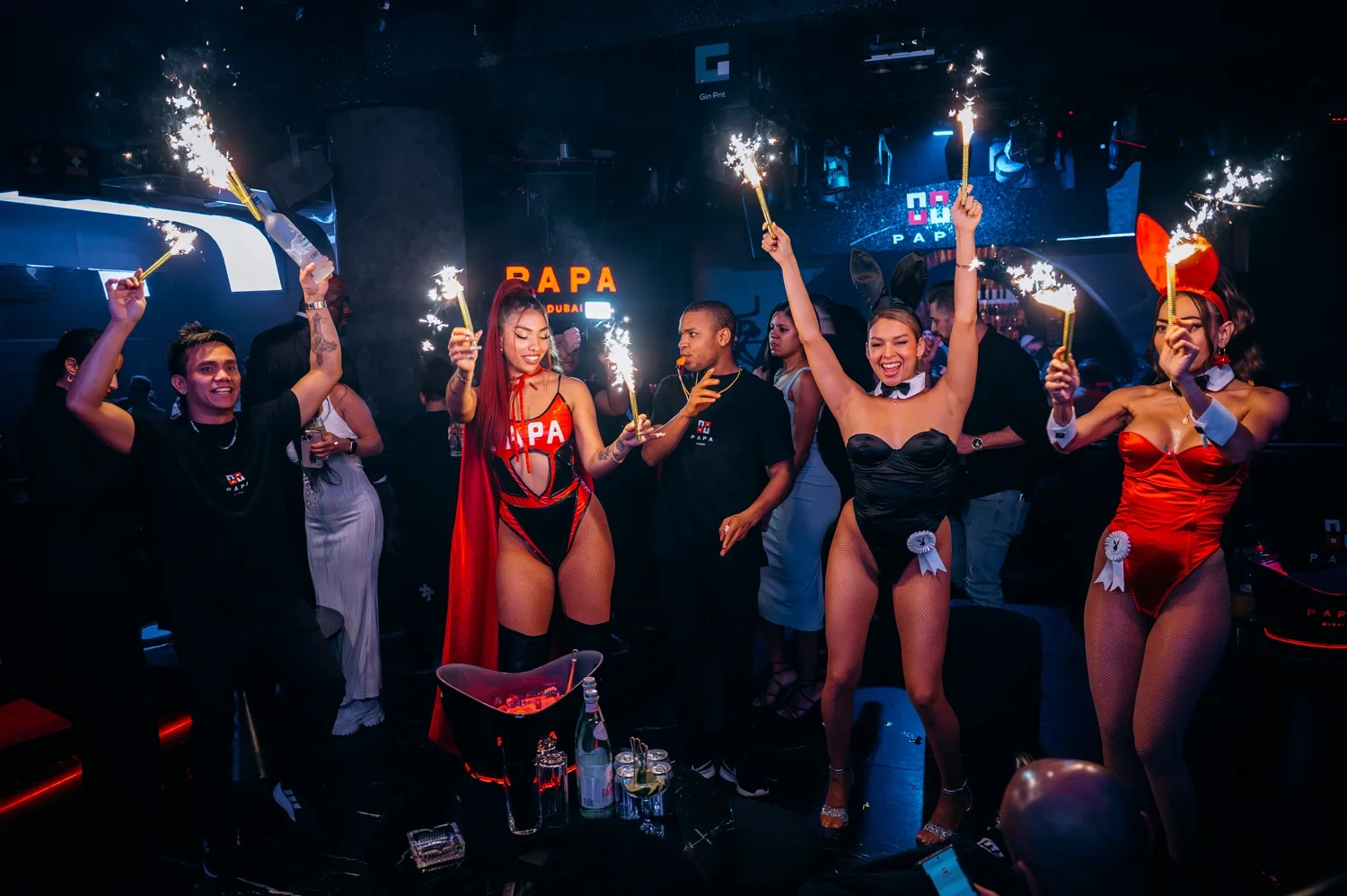 PAPA Dubai performers in bunny and red costumes holding sparklers around a table with bottle service
