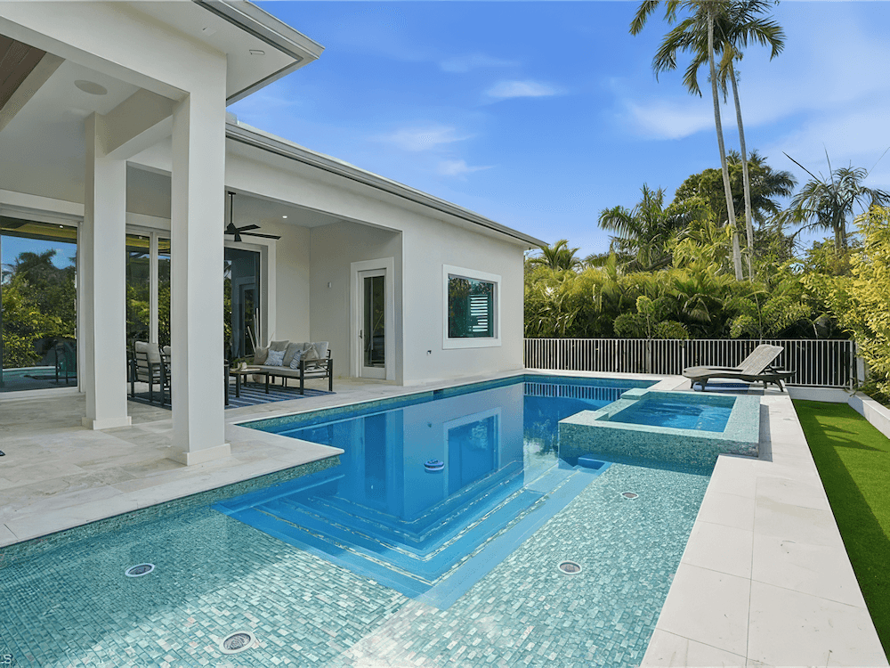 a large modern pool with an open backyard and hot-tub