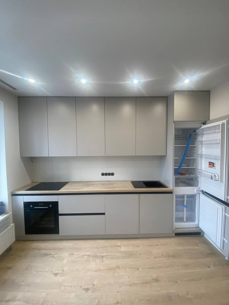 Кухня з білим холодильником, світлими фасадами та LED-підсвіткою