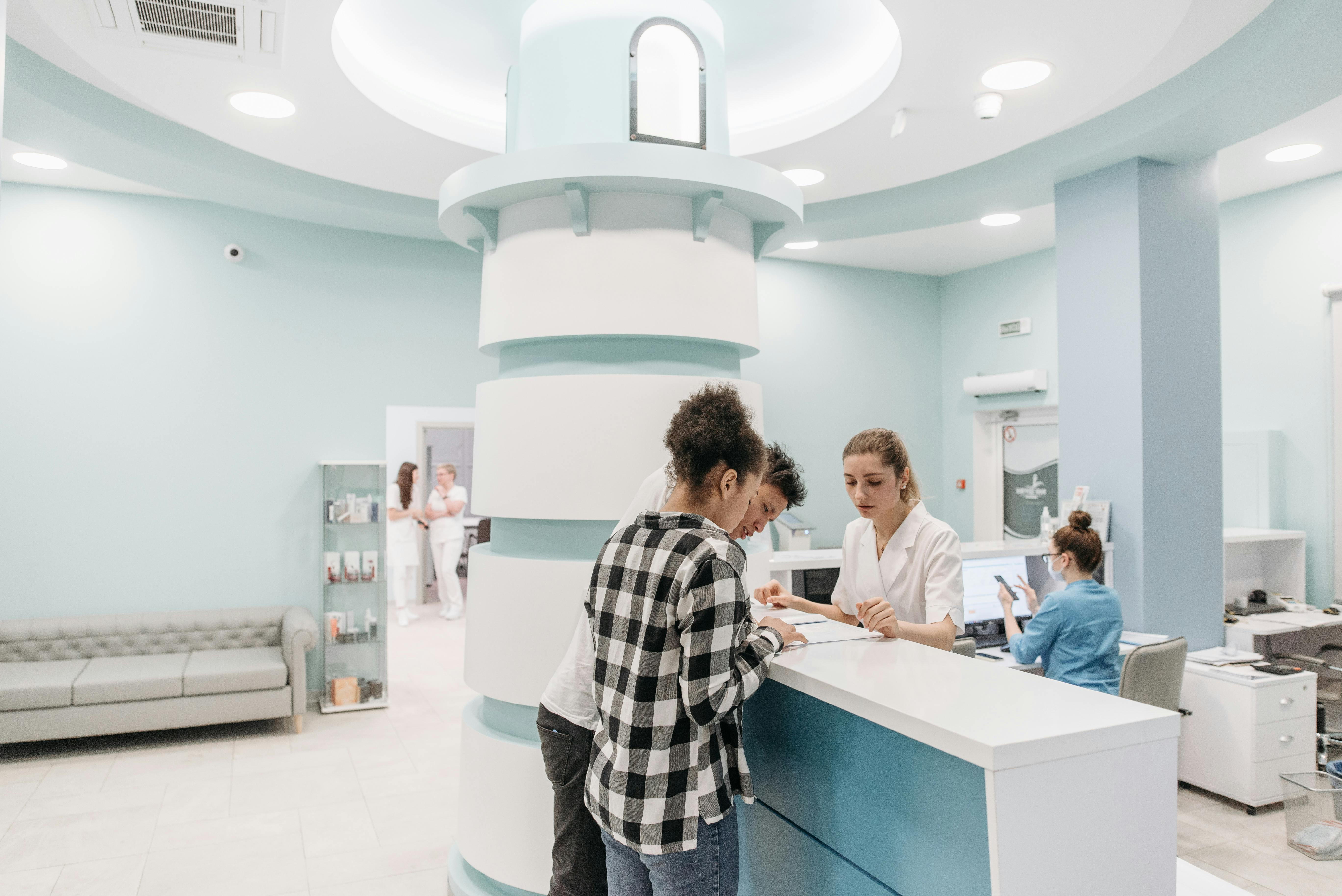 A picture of patient checking in at modern dental clinic reception desk with staff
