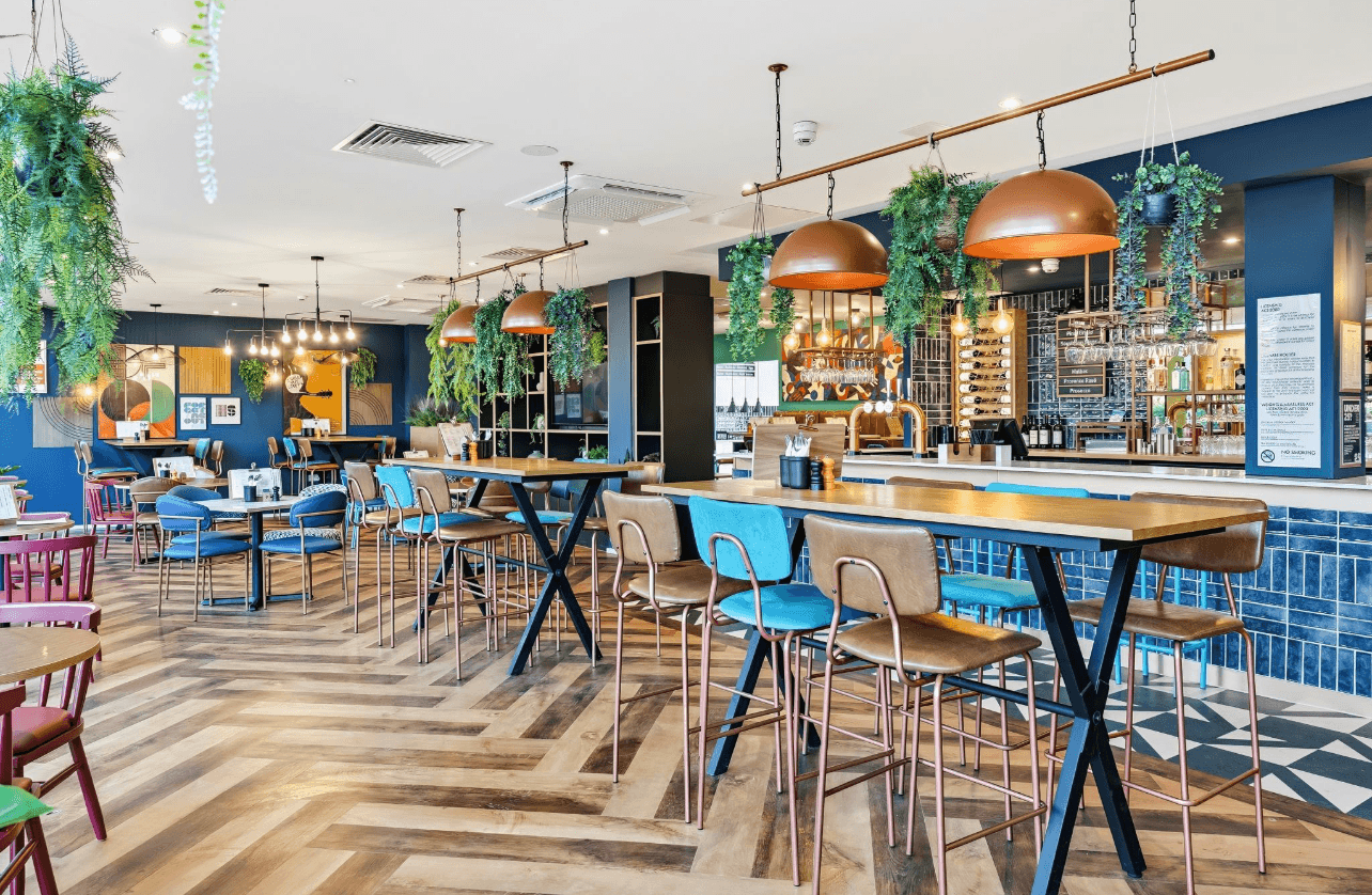 A winding road cuts through rocky terrain, surrounded by patches of green grass and illuminated by sunlight.