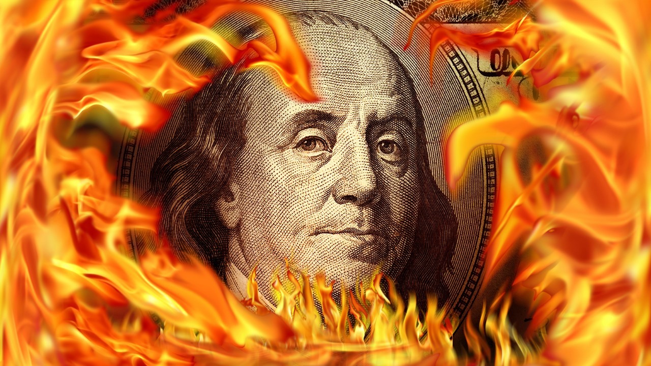 Conceptual finance image of burning dollar bill and fire flames