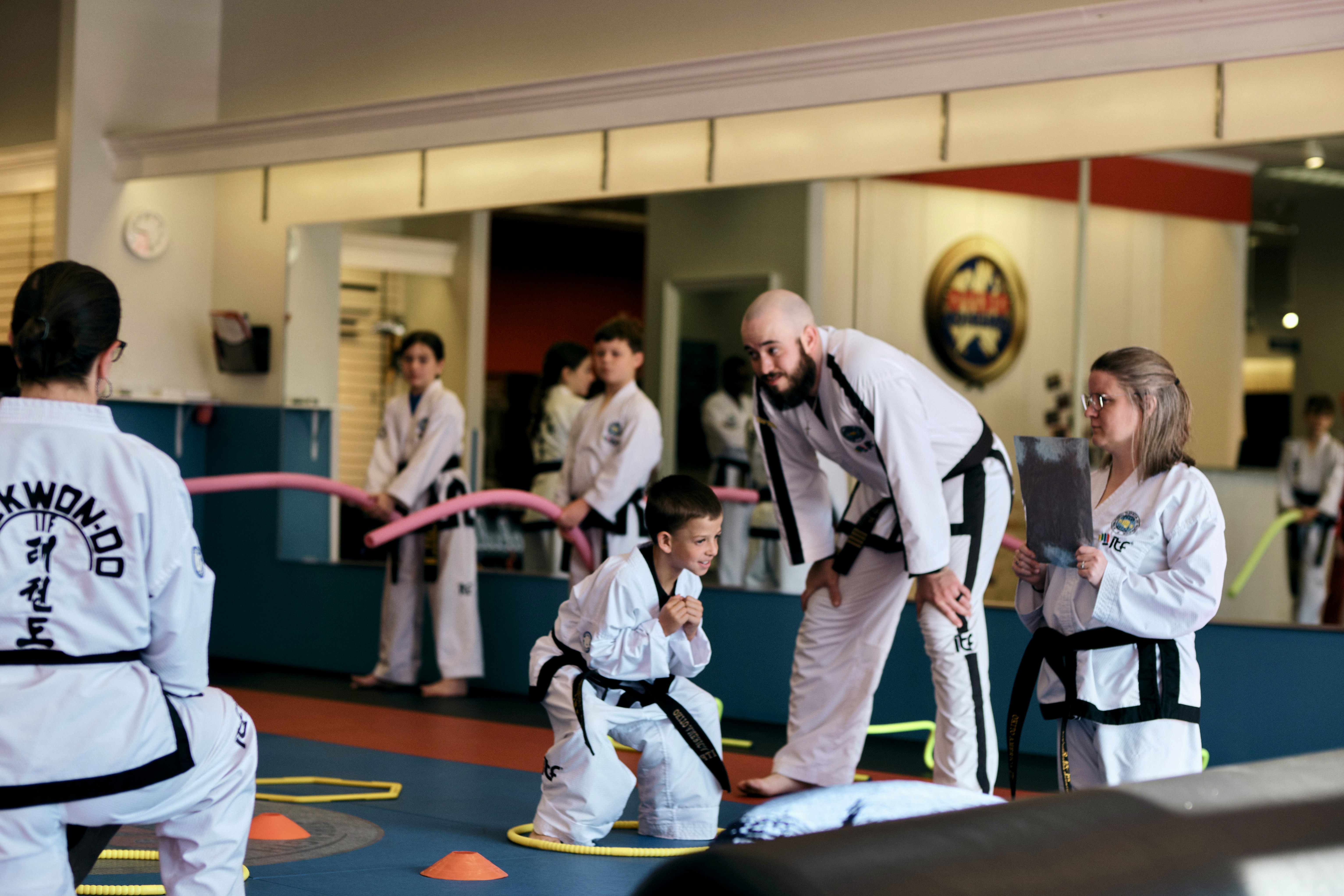 Martial Arts class with black belts and student completing an obsticle course