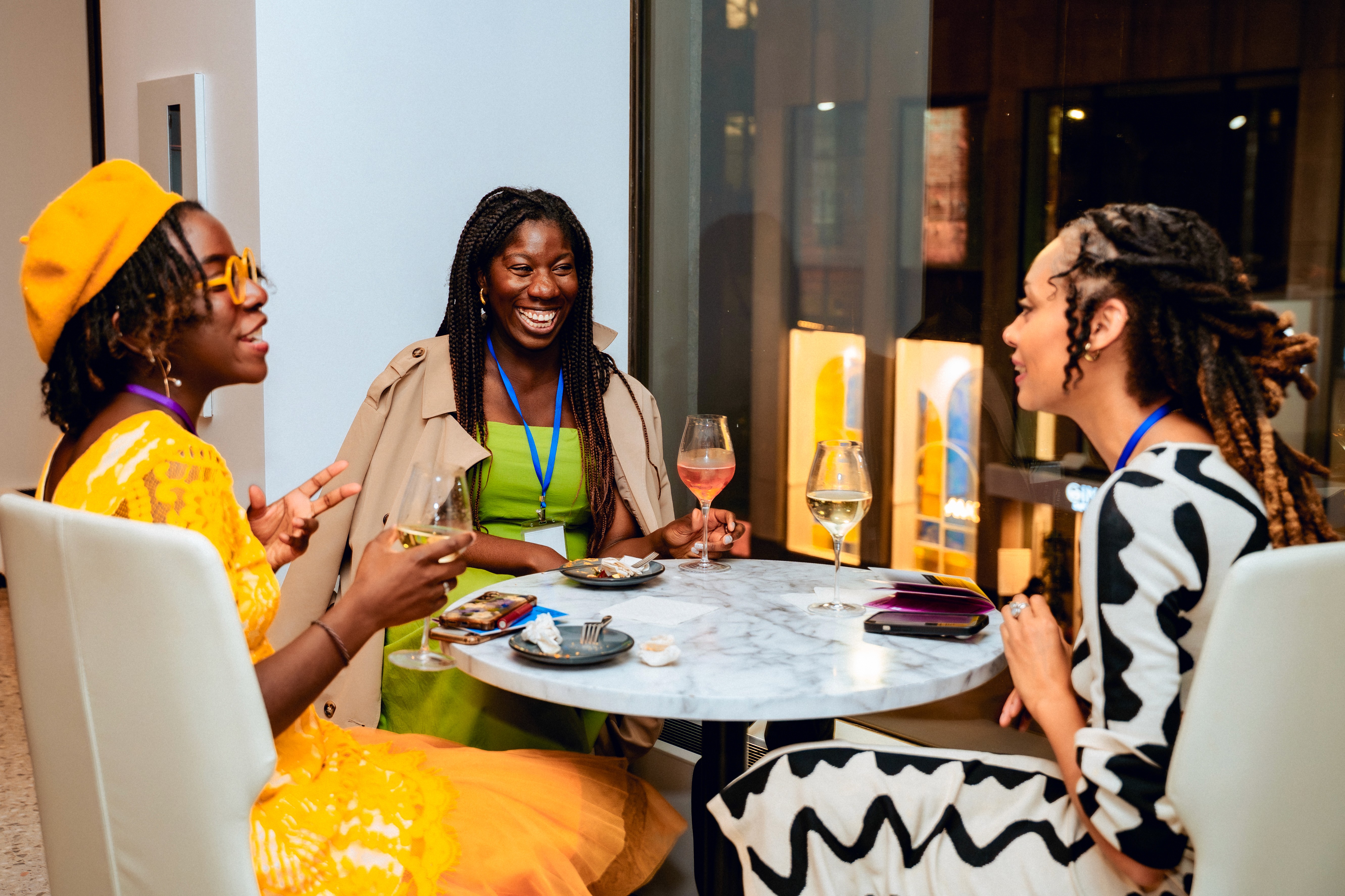 Image of three women sitting around a table laughing at the 2025 WIN Awards