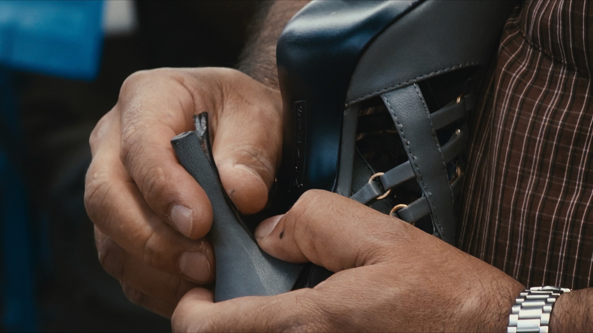 Hands shaping a shoe upper in a factory, Maddman