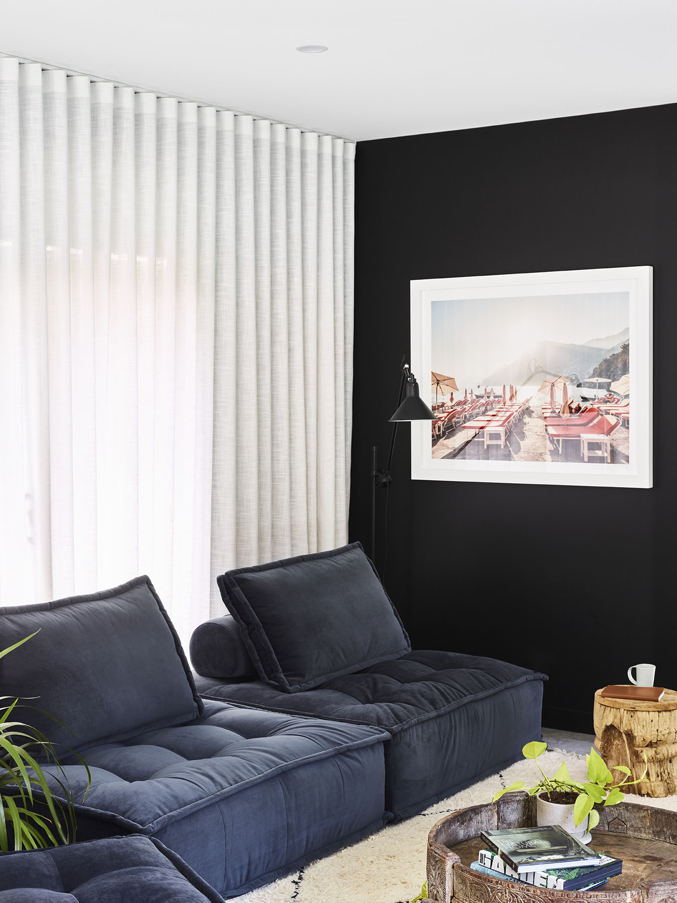 Lounge with navy modular sofa, black feature wall, and soft natural light.