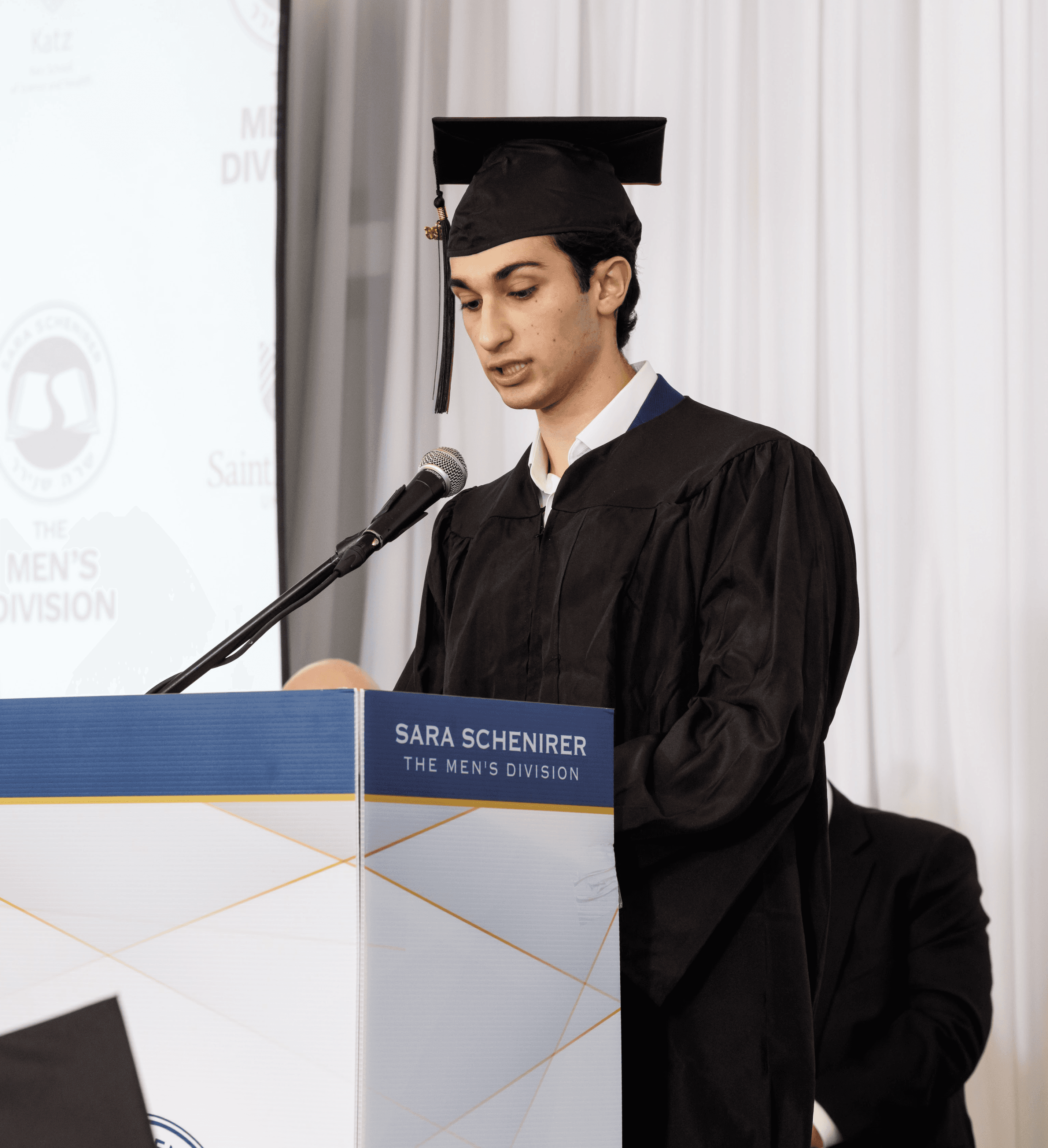 man holding the back of his head while smiling near brick wall