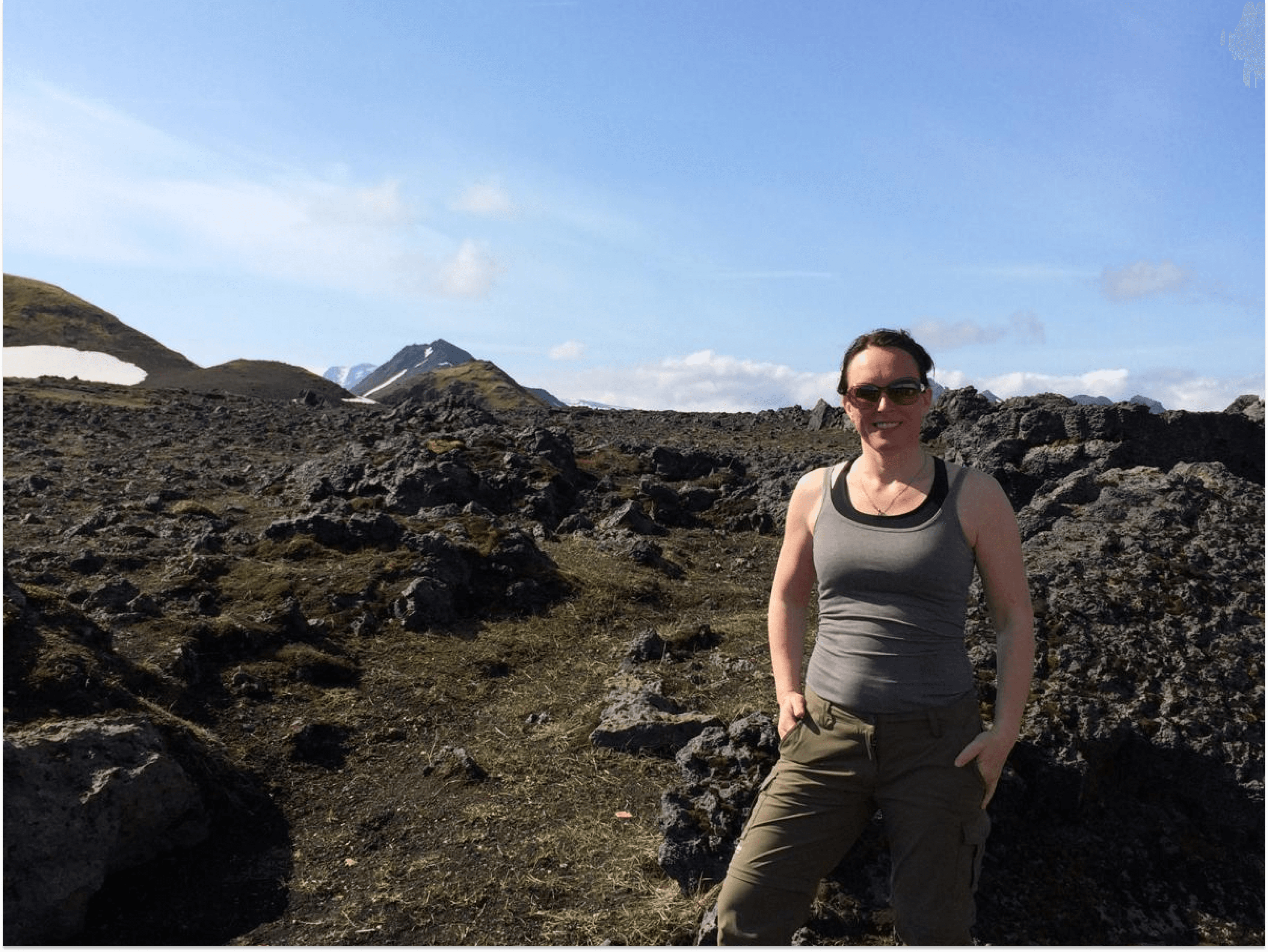 A woman smiling into the camera in front of icelandic landscapes