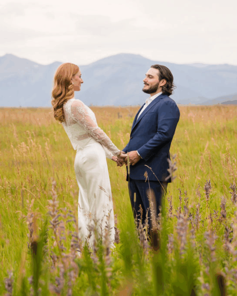 Newlyweds facing each other in a wildflower meadow