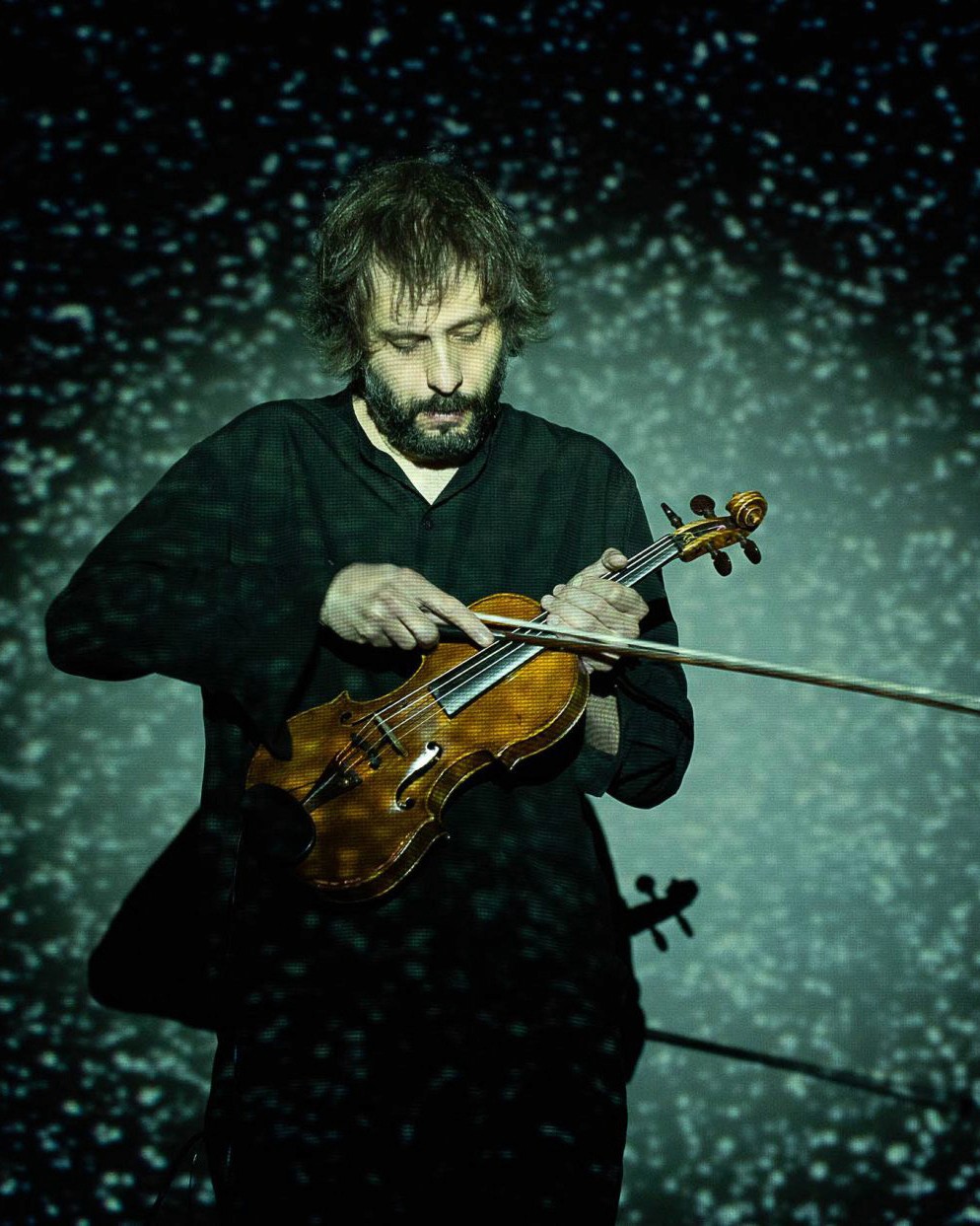 Man playing violin with blue granular texture projection