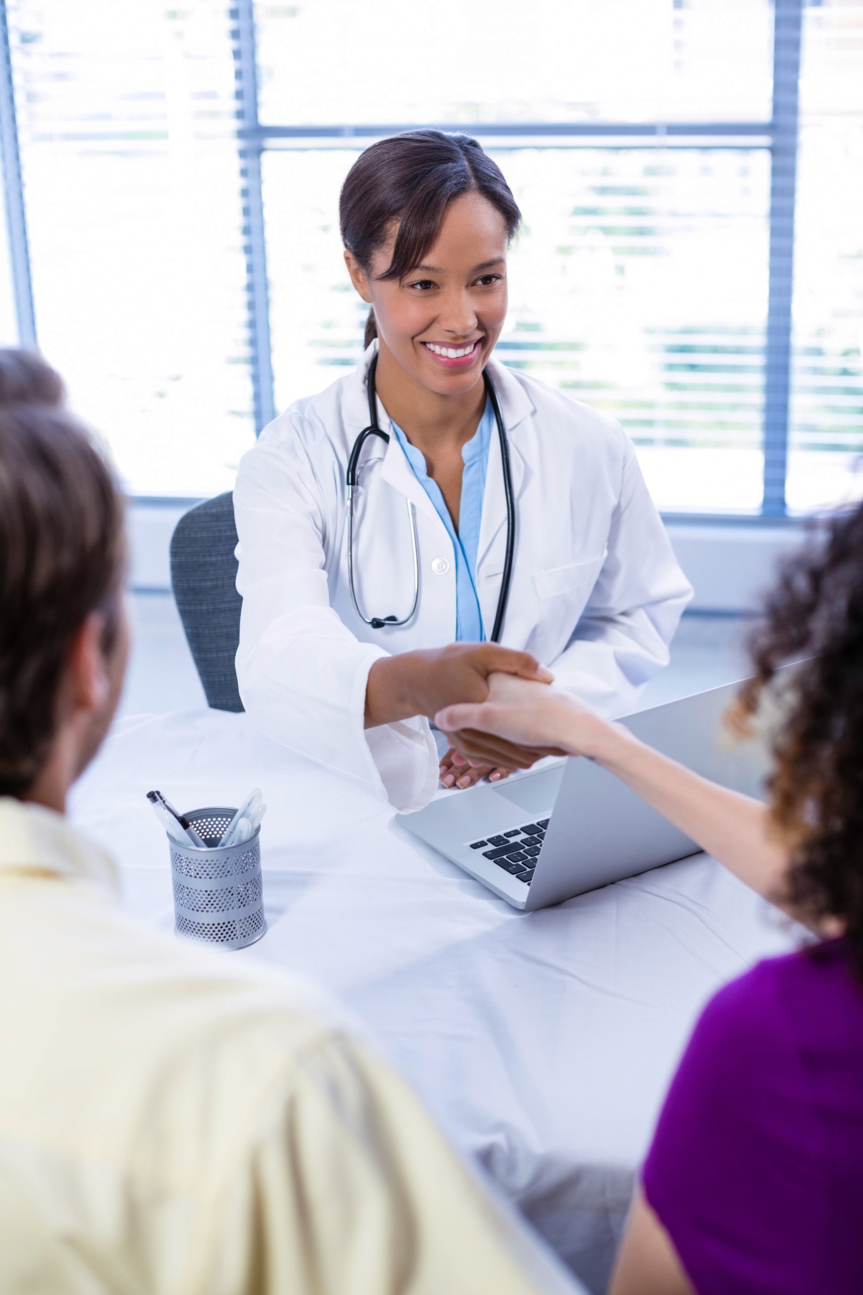 Doctor and woman shaking hands in clinic