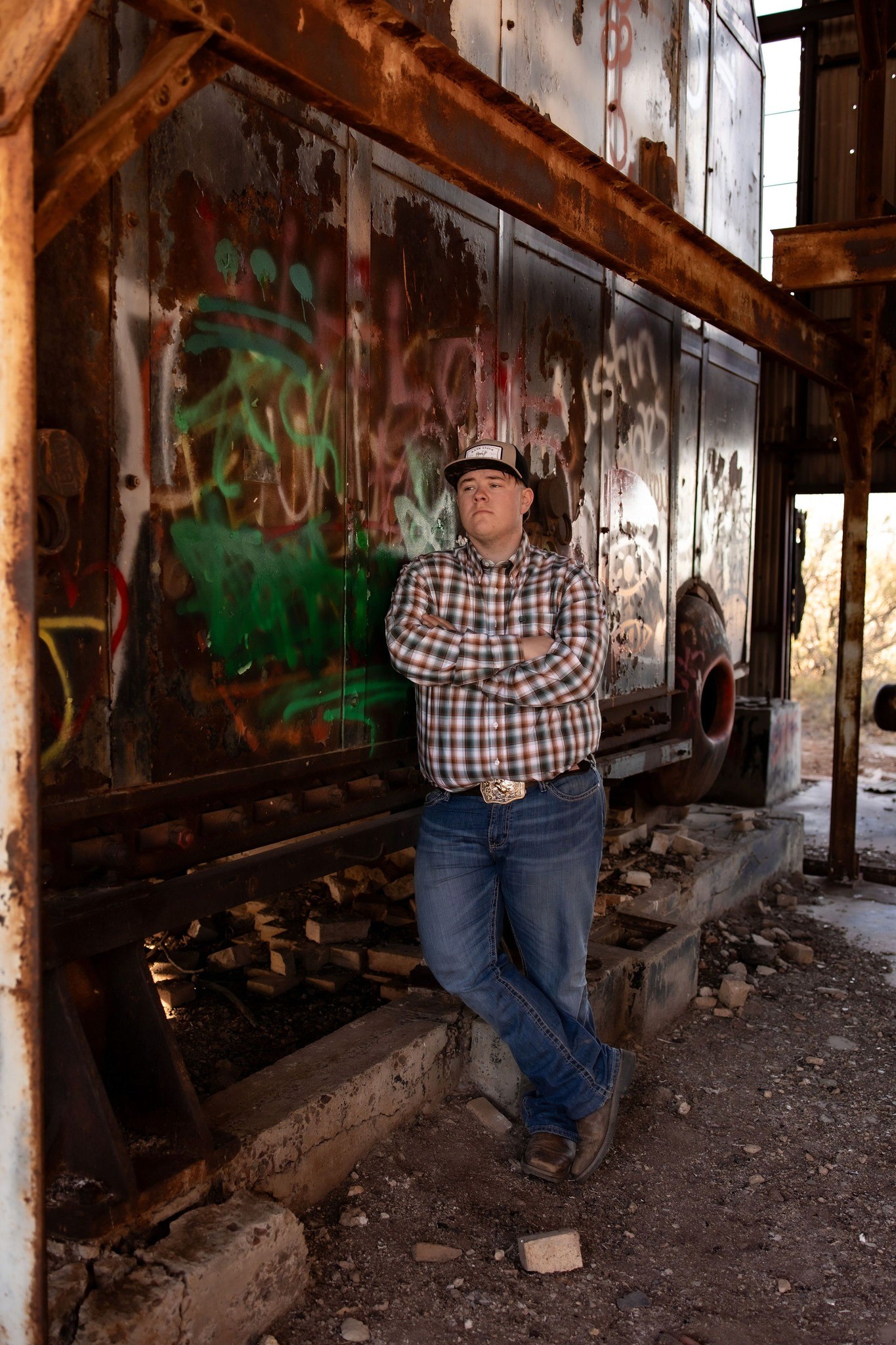 A man stands tall leaning against an abandoned building.