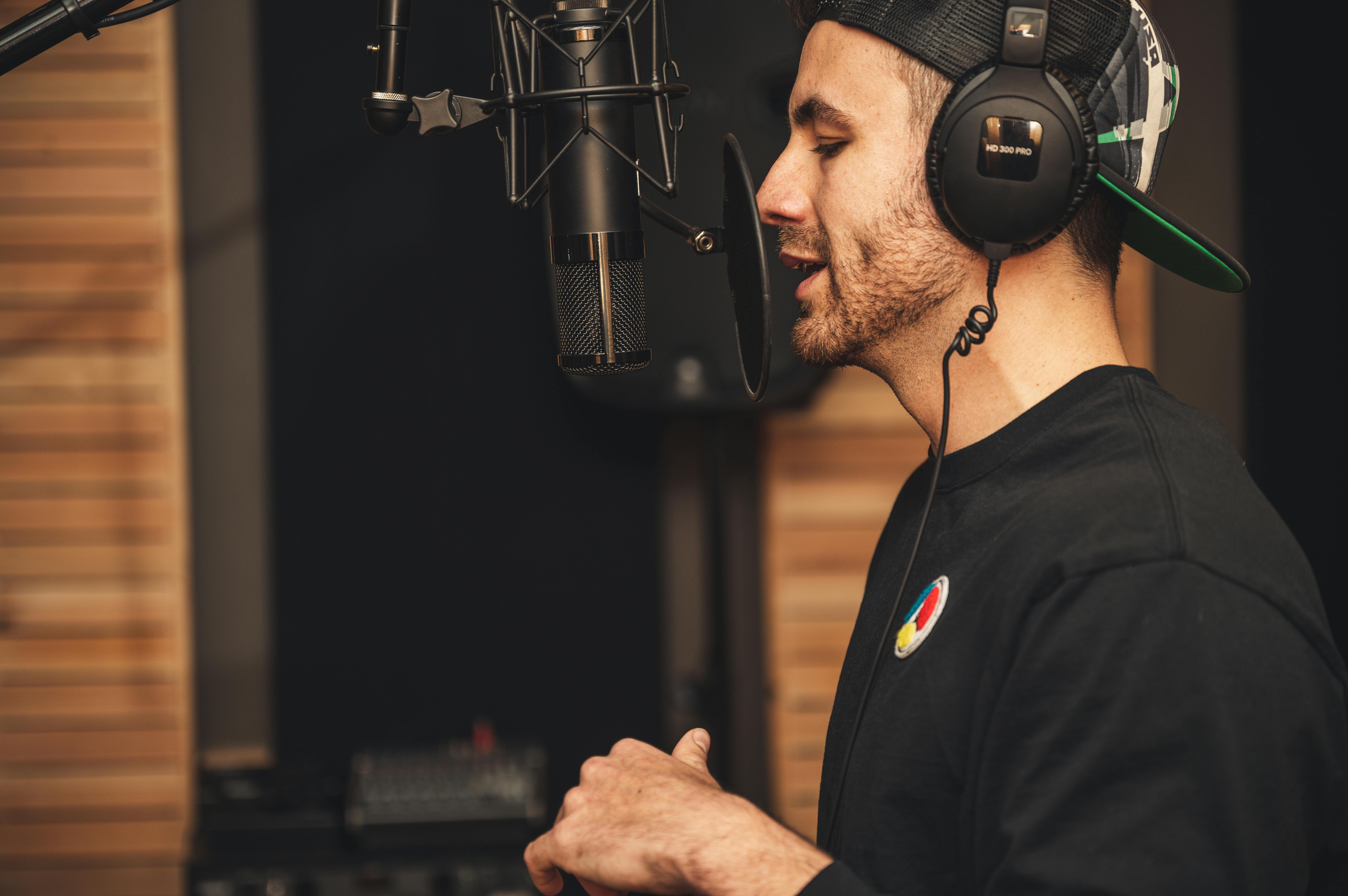Male singer wearing headphones recording vocals in a professional studio—returning to singing after a break.