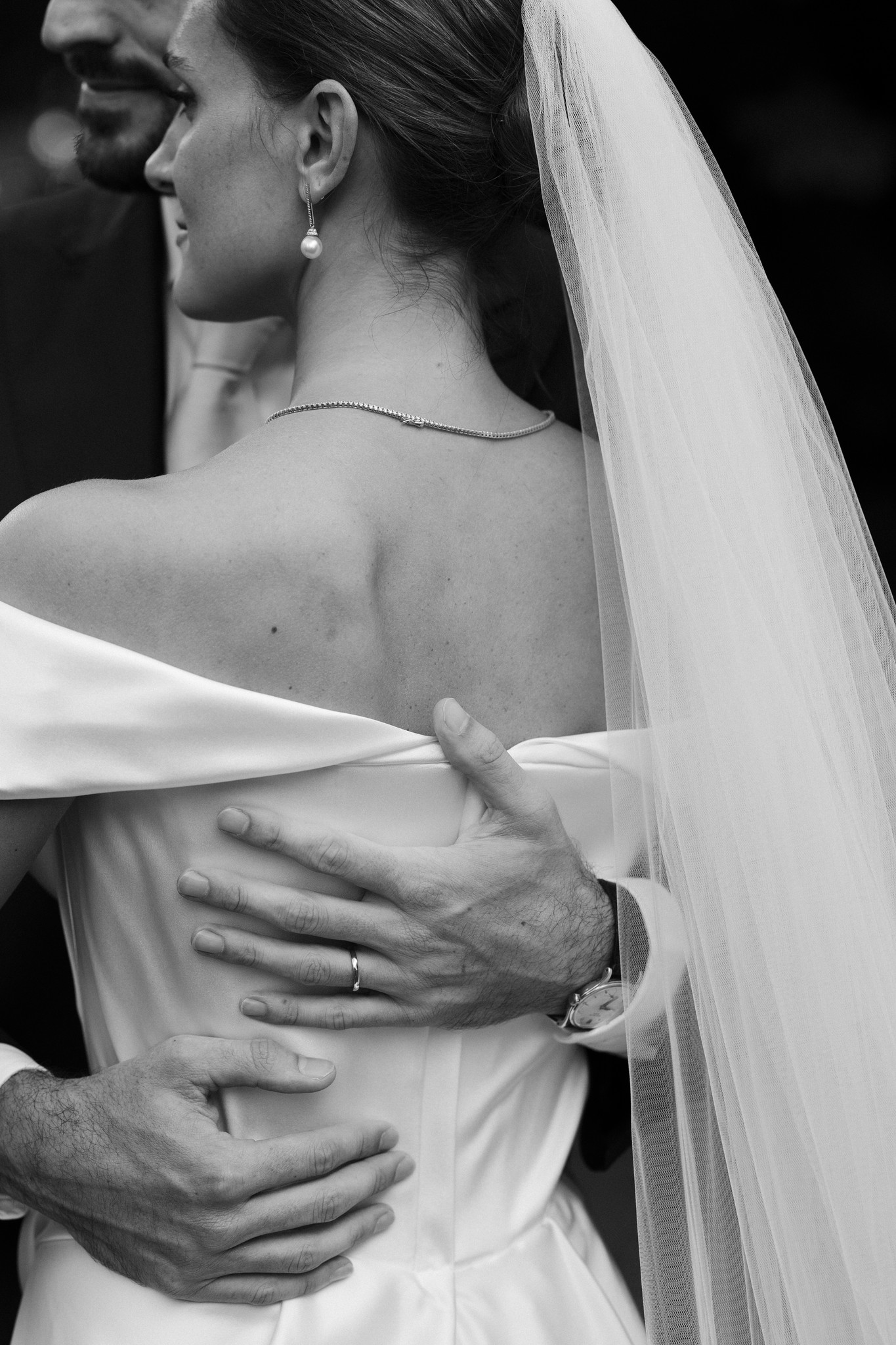 Sposa abbracciata dallo sposo, velo di tulle sulle spalle, ritratto intimo in bianco e nero al Castello di Scipione