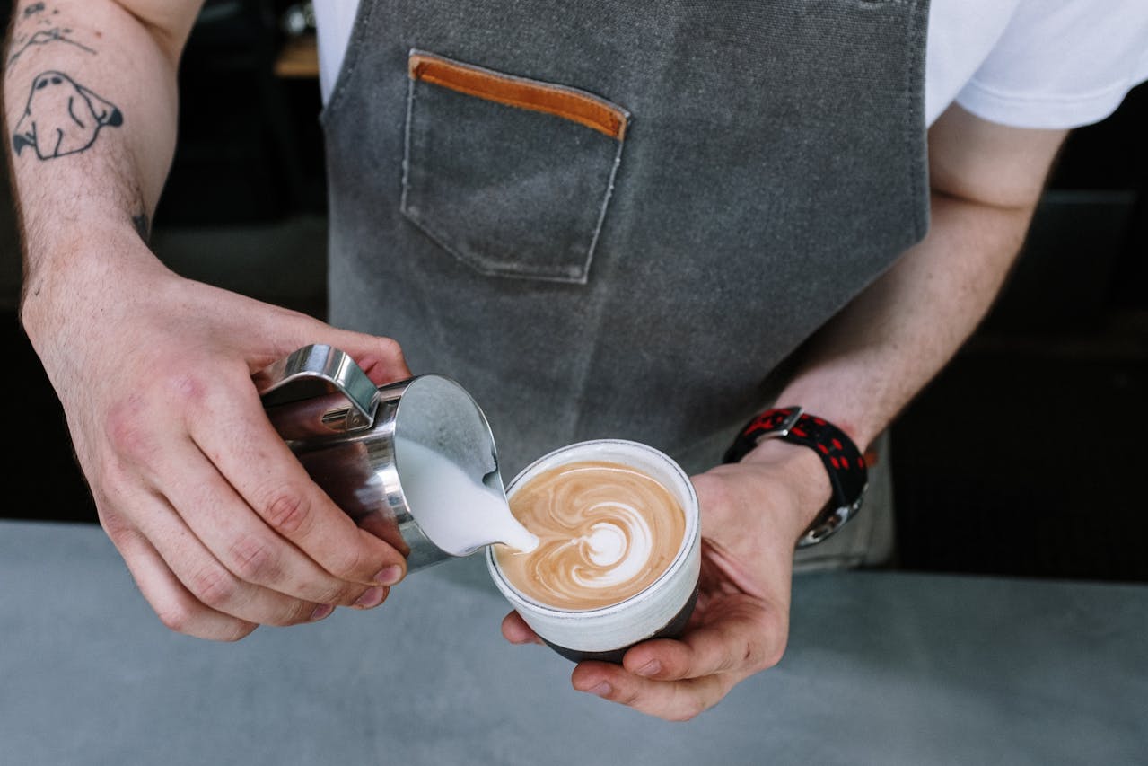Persona sosteniendo una taza de cerámica con capuchino