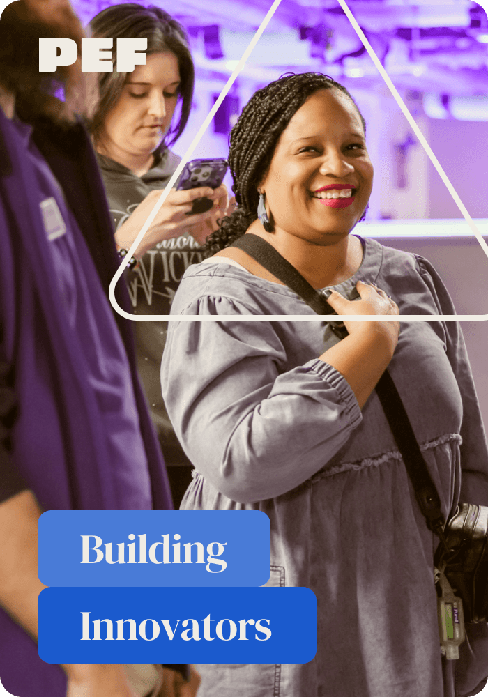 Femail teacher standing in a group of fellow teachers, smiling at the camera.