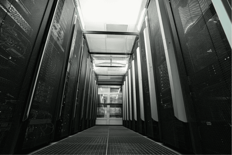 A large data server room with black server towers with blinking lights