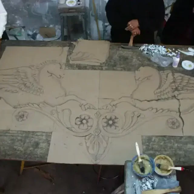 A full-size mosaic cartoon laid out in numbered sections on the studio bench, with tesserae and tools.