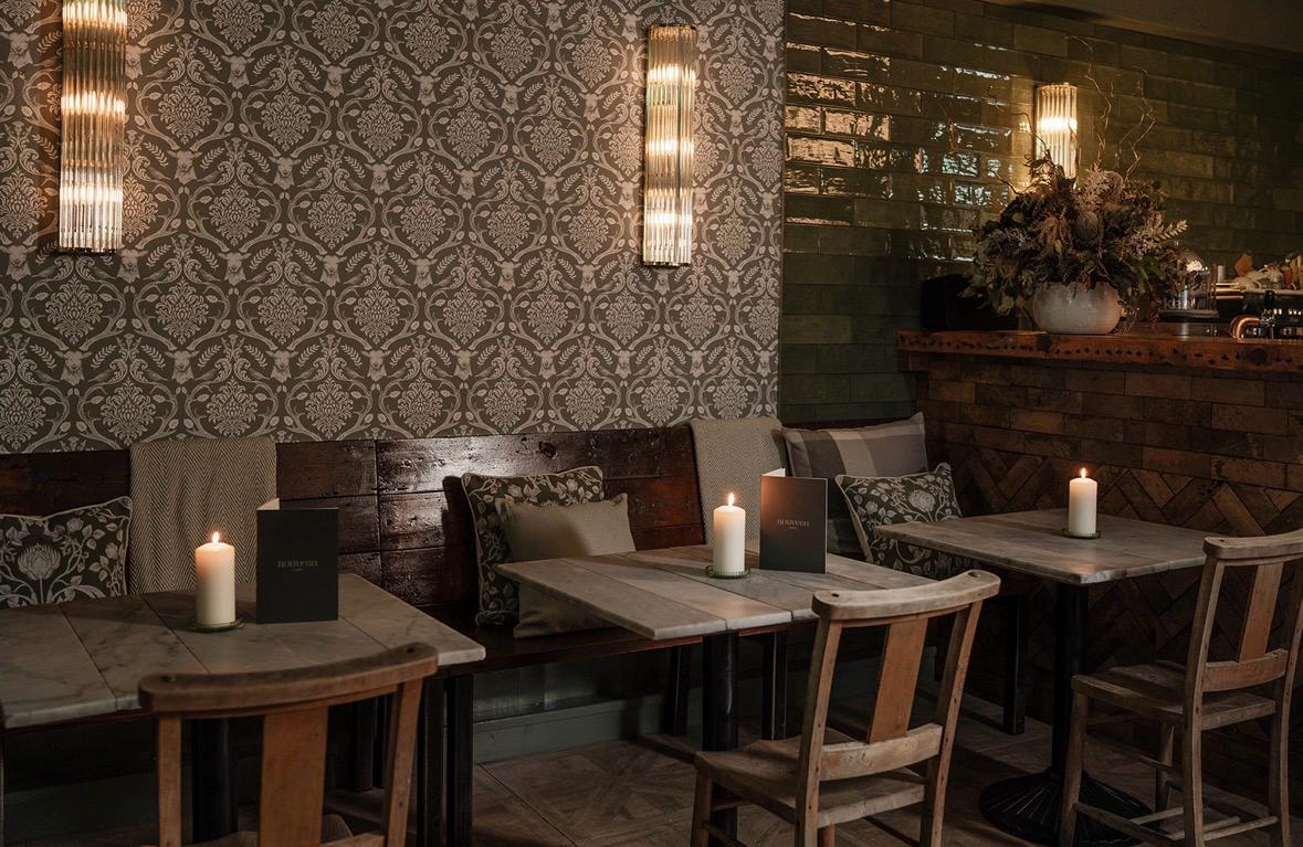 White plate with roasted chicken served in a golden sauce with herbs and capers, placed on a terrazzo tabletop in sunlight.