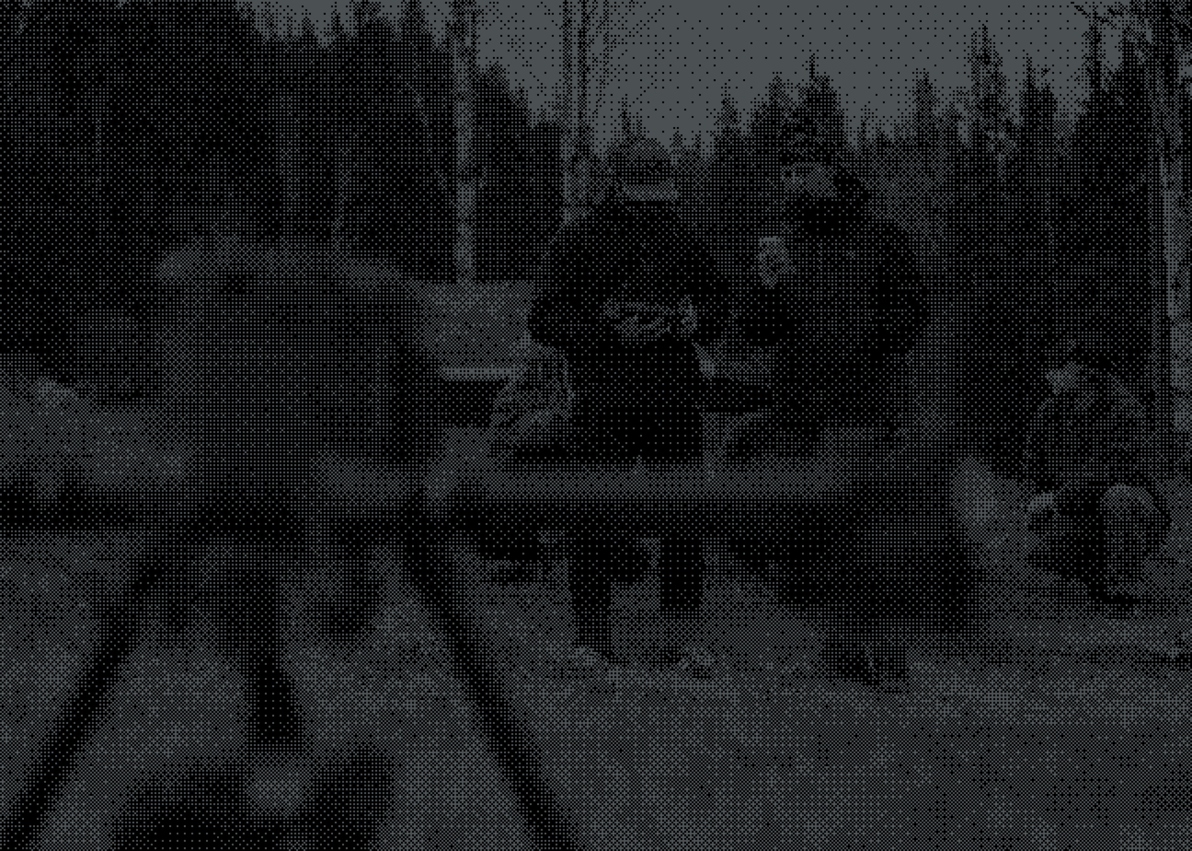 Two people dressed warmly stand over a drone with a remote control in hand.