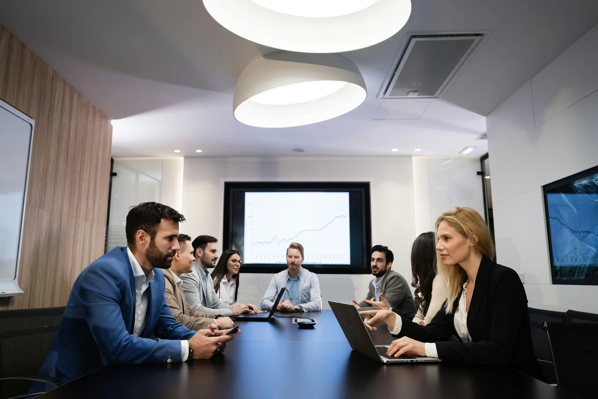 Executives seated around large boardroom table in formal meeting