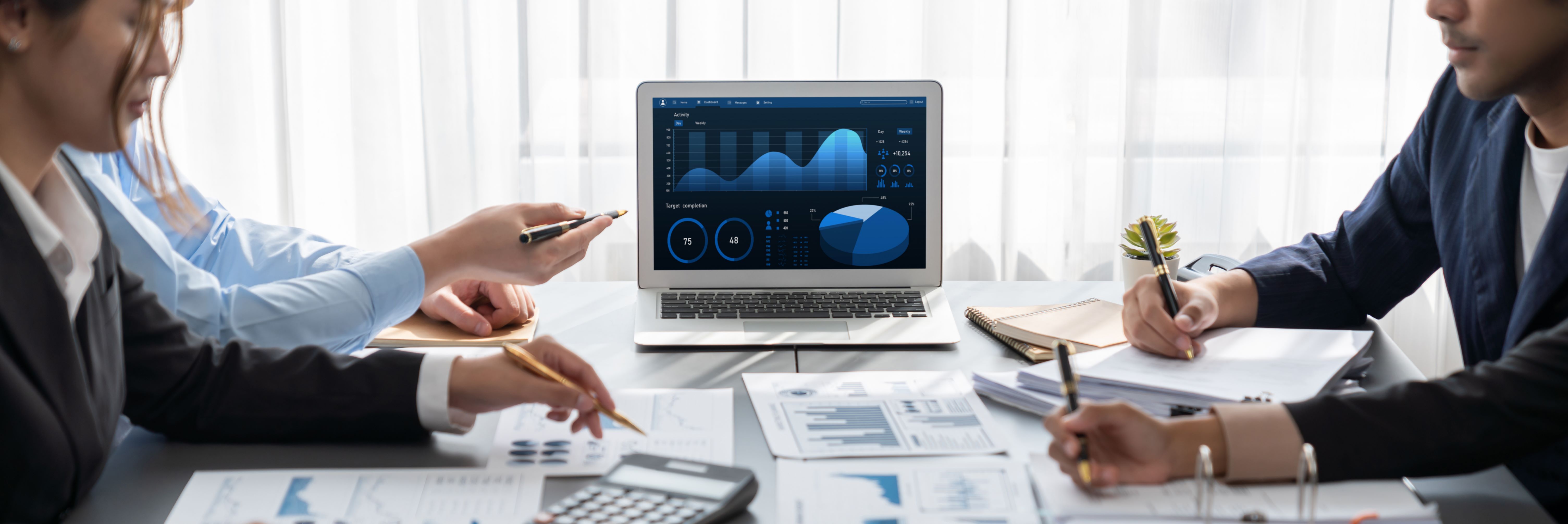 a group of people sitting around a table with laptops