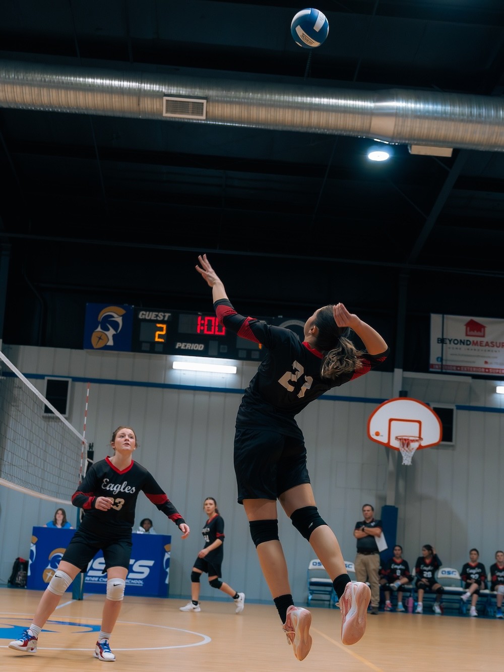 Varsity girl in volleyball suspended in air, about to attack the ball
