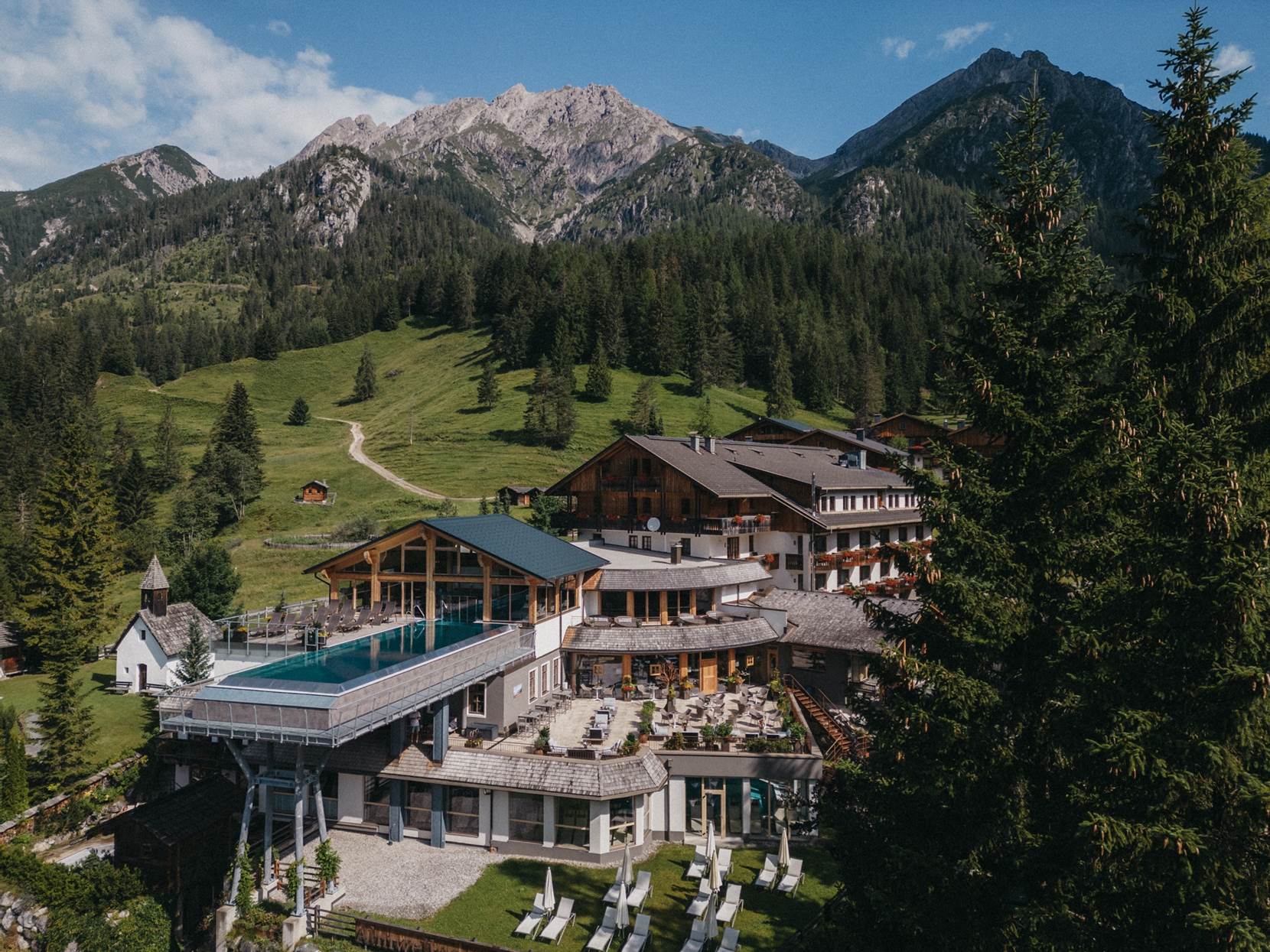 Außenansicht des Hotel Almwellness Tuffbad vor einer Bergkulisse.