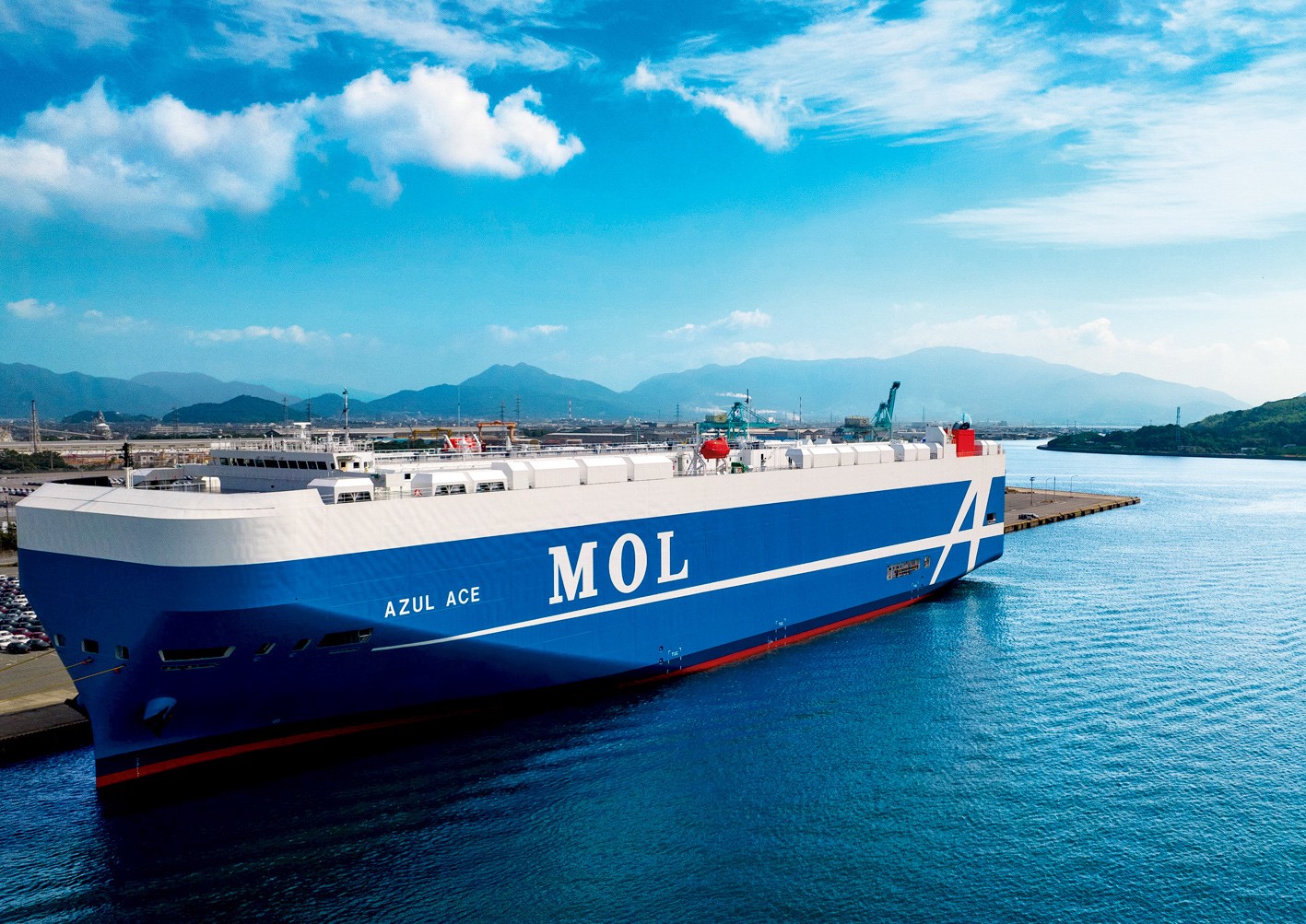 Blue MOL ship docked with mountains in the background