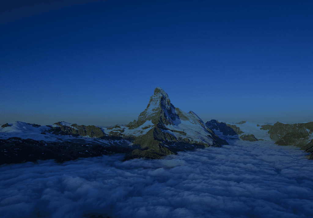 Vue aérienne du sommet enneigé et pyramidal du Cervin, s'élevant au-dessus d'une vaste mer de nuages duveteux au lever du soleil.