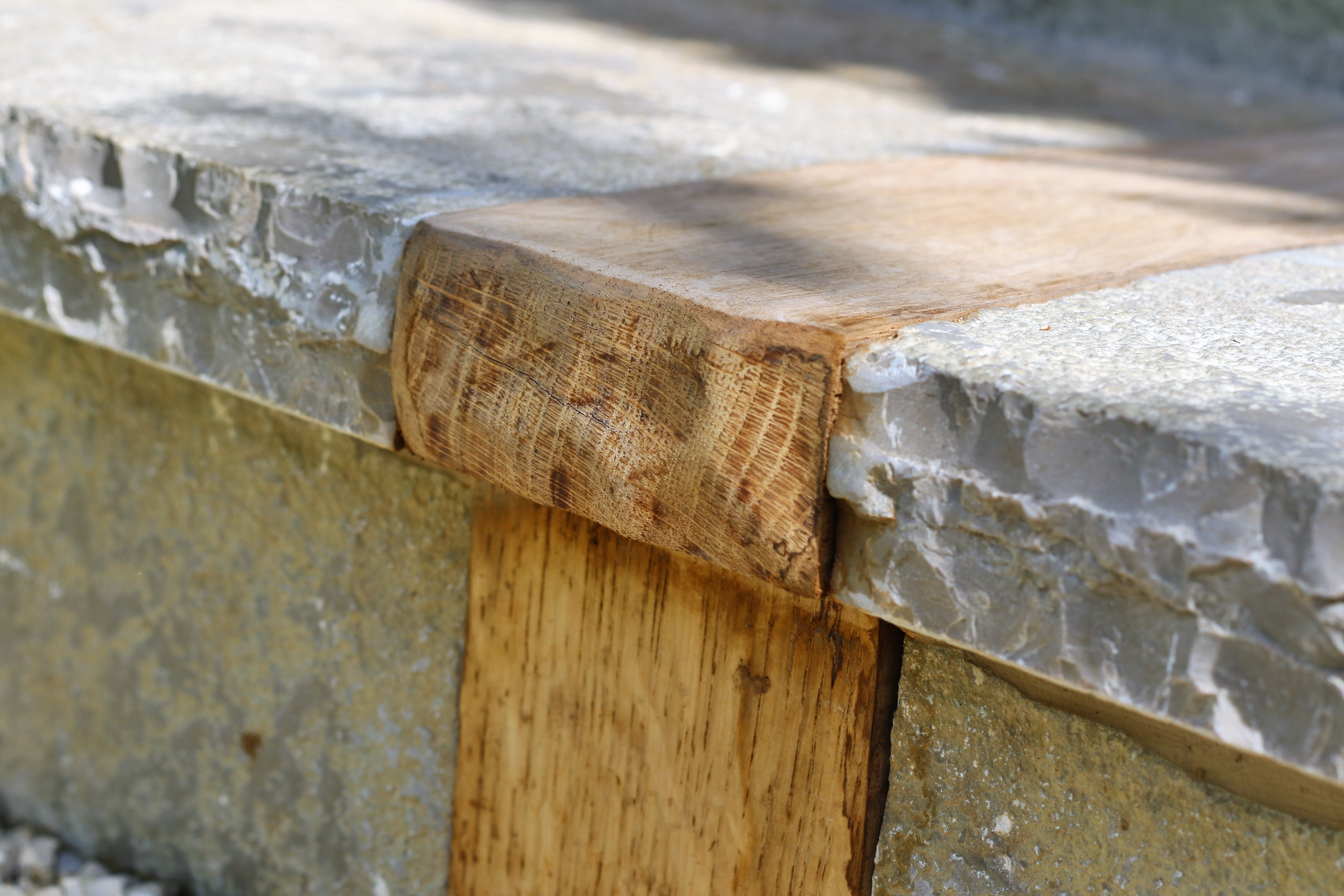 Close-up of a wooden joint attached to a stone surface, showcasing a natural wood grain and smooth edges.