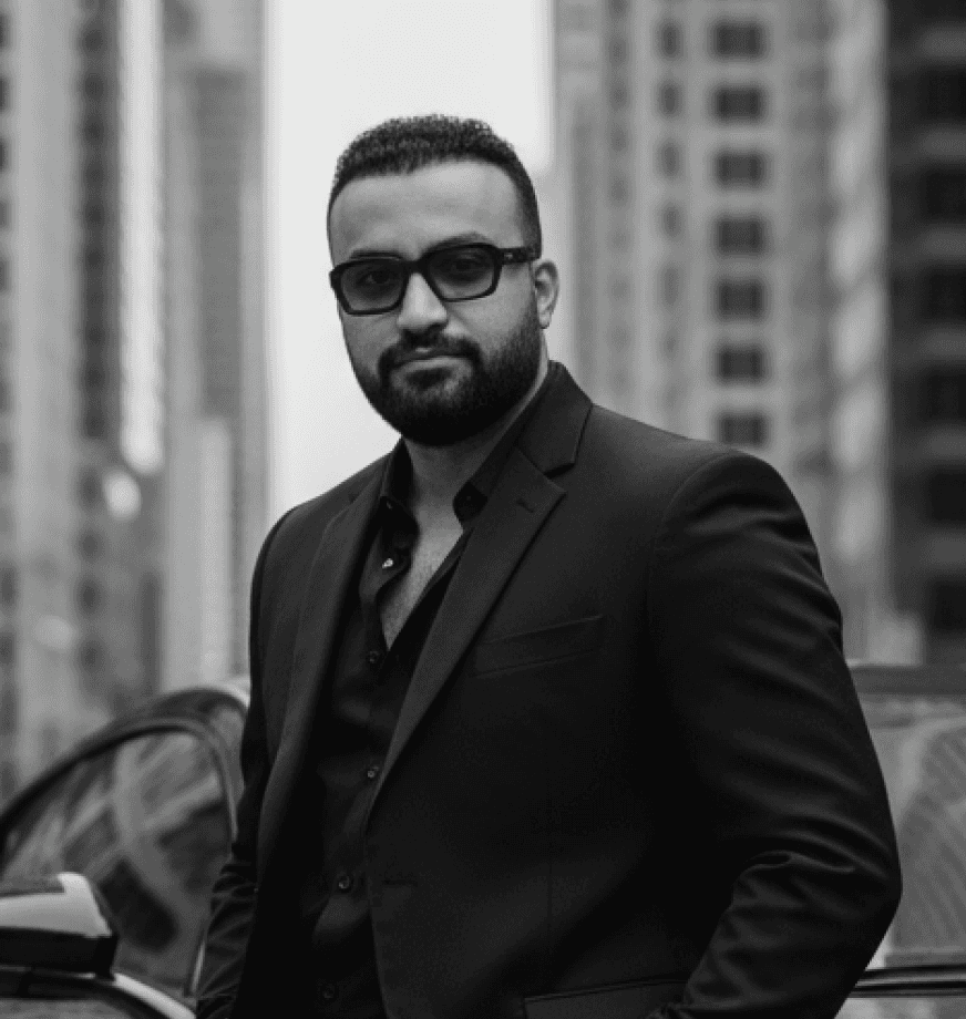 A young person in a gray shirt stands in focus against a blurred background with moving figures, creating a striking visual contrast.