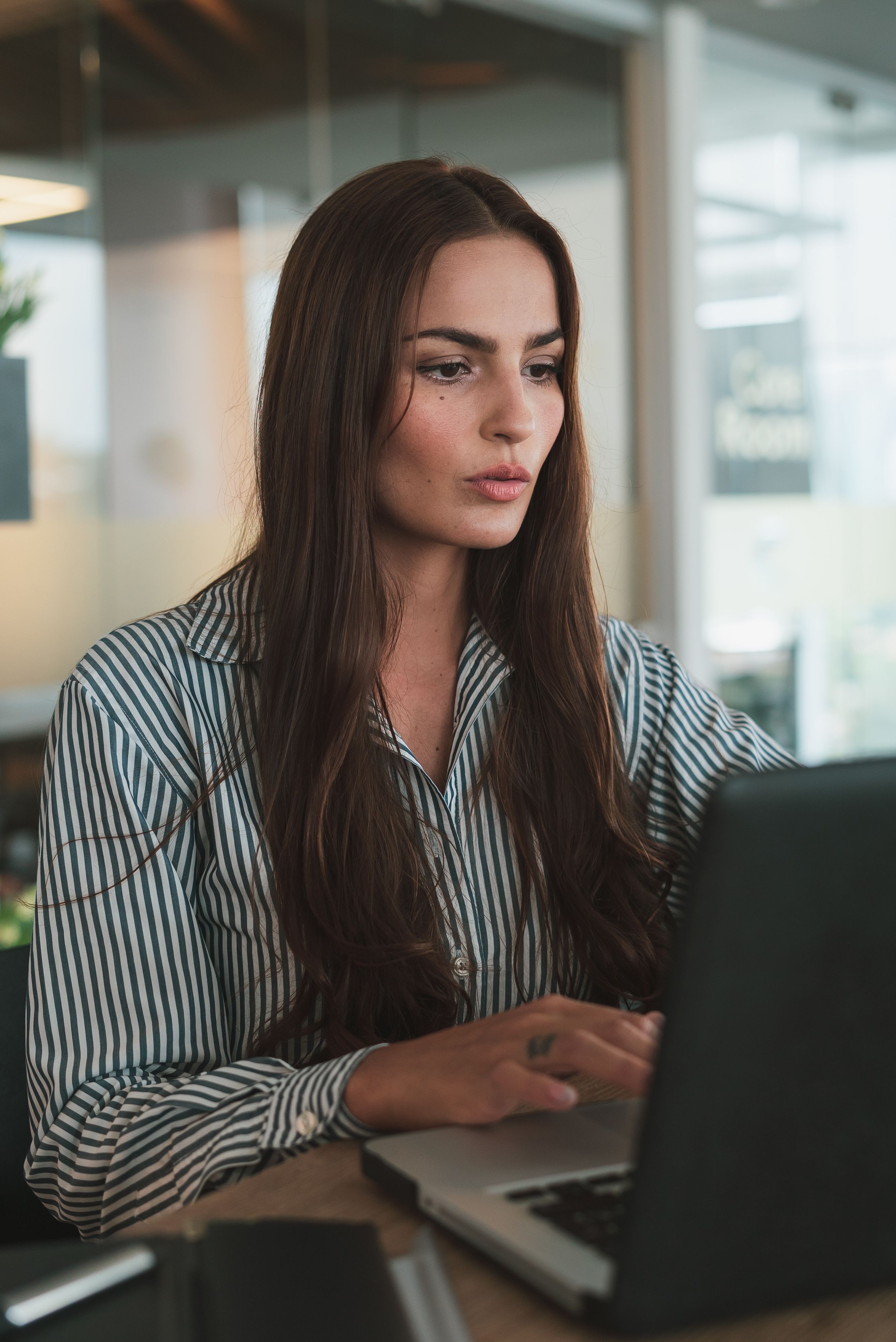 focused-businesswoman-with-long-hair-working-on-a-laptop-in-a-modern-office-envi - los-muertos-crew (pexels)