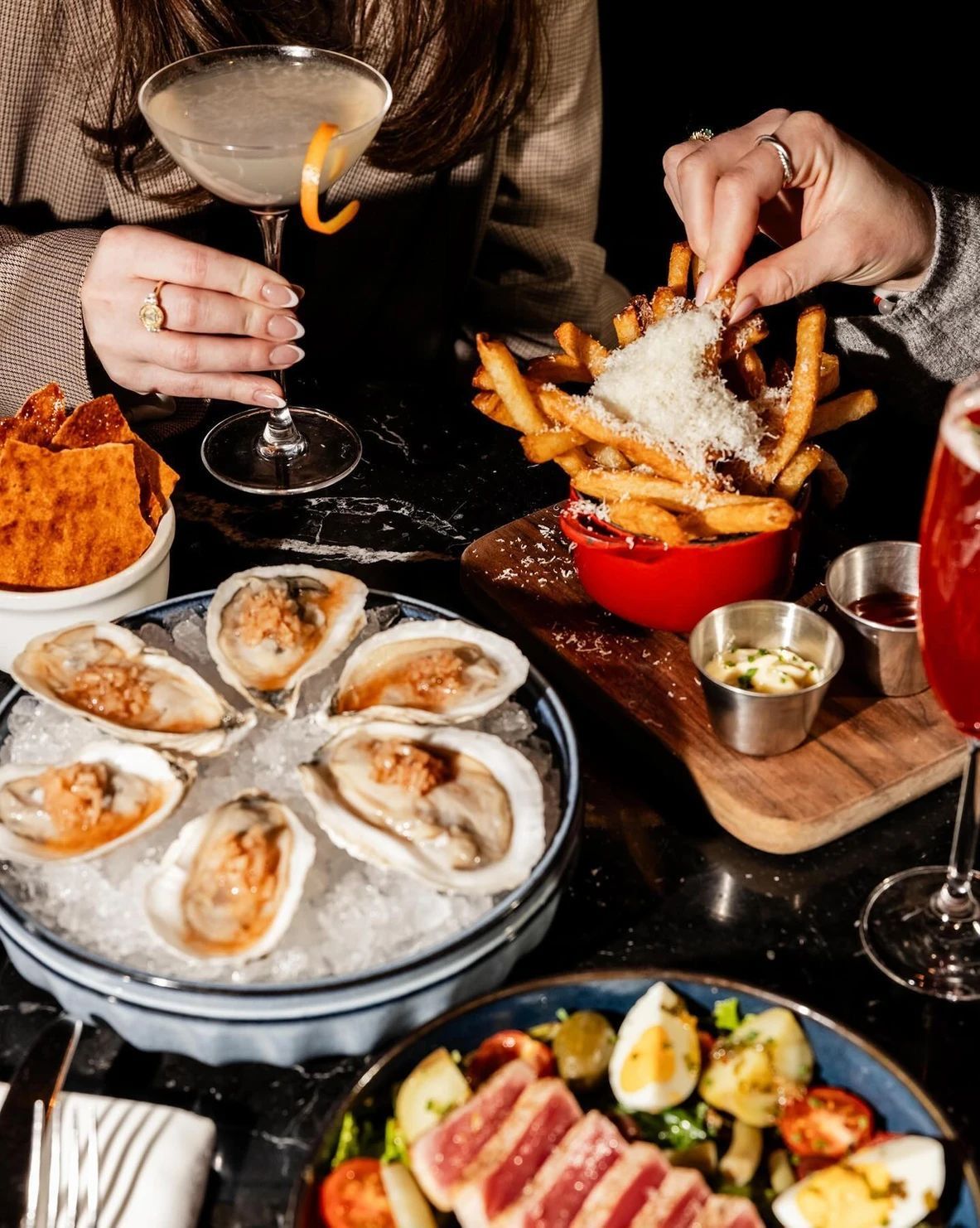 Upscale dining spread with oysters, cocktails, and artisanal appetizers, highlighting the fine tuned methods and elevated culinary craftsmanship practiced at Dhoom Toronto.