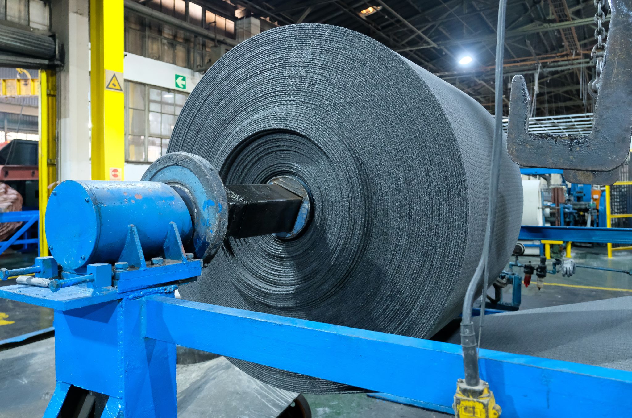 A young woman with long hair smiles while standing against a green backdrop, wearing a casual dark sweater.