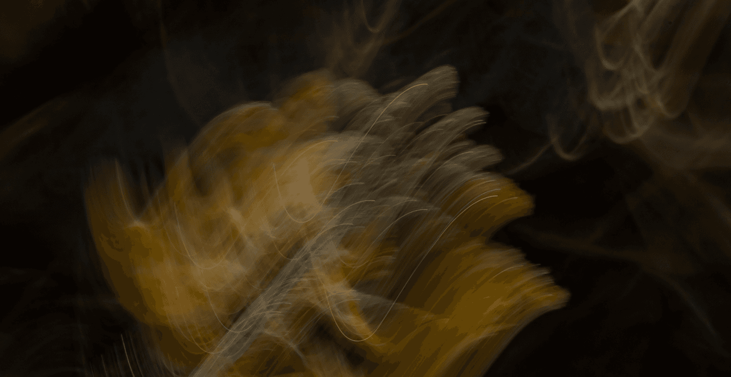 Abstract motion-blurred light patterns in warm gold and green tones against a dark background.