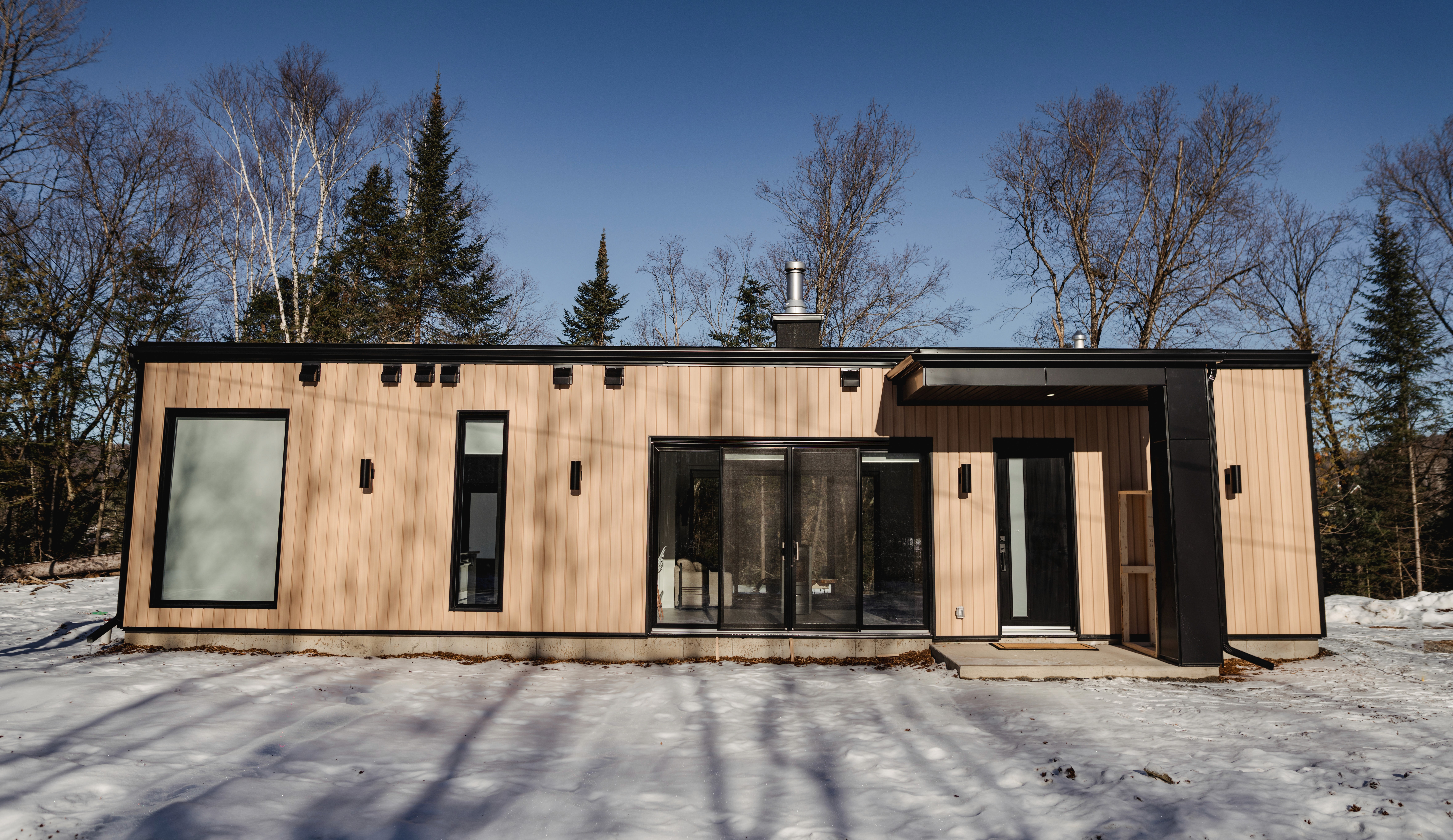 Maison contemporaine de plain-pied avec revêtement en bois en hiver
