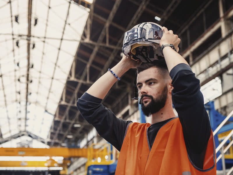 Technicien relevant sa visière sous une verrière industrielle
