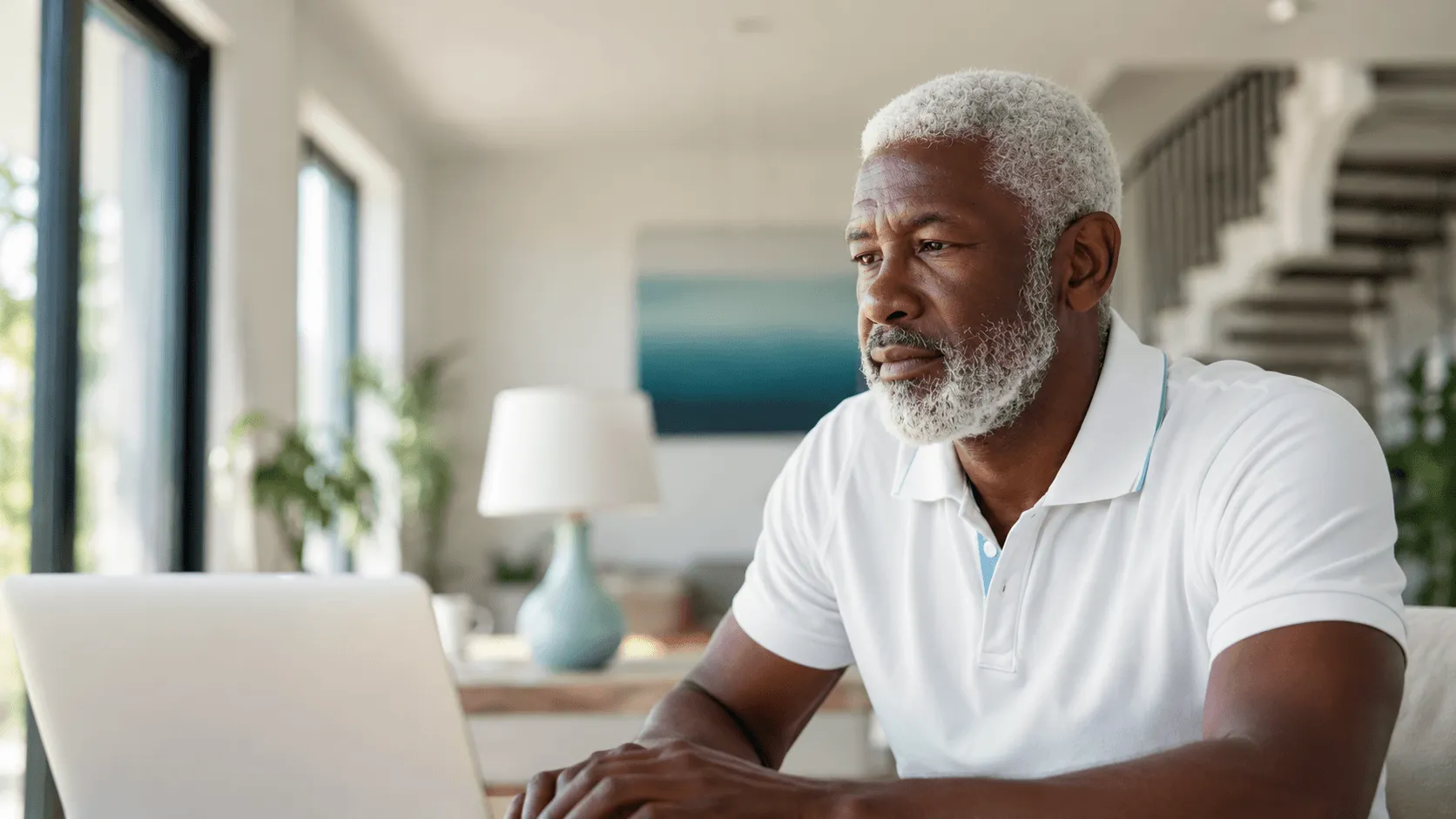 Man with grey hair and beard on laptop