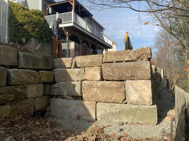 Price Landscape and Construction onsite at a residential home working on a large rock retaining wall