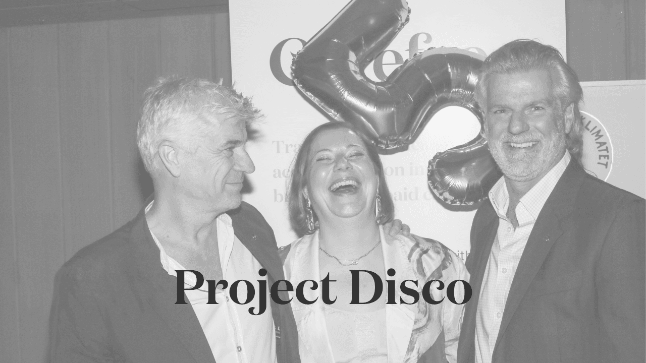 Three people smiling and laughing at a celebration event with large metallic balloon shaped like a '5' in the background. The text 'Project Disco' is overlaid in bold black font.