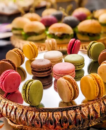 Macarons franceses de colores en torre dorada para mesas de postres de matrimonios en Santiago.